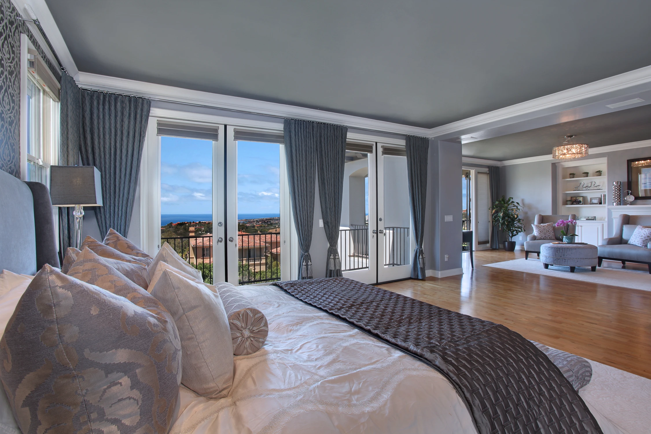 Master bedroom with upholstered bed, dark drapery, and balcony view