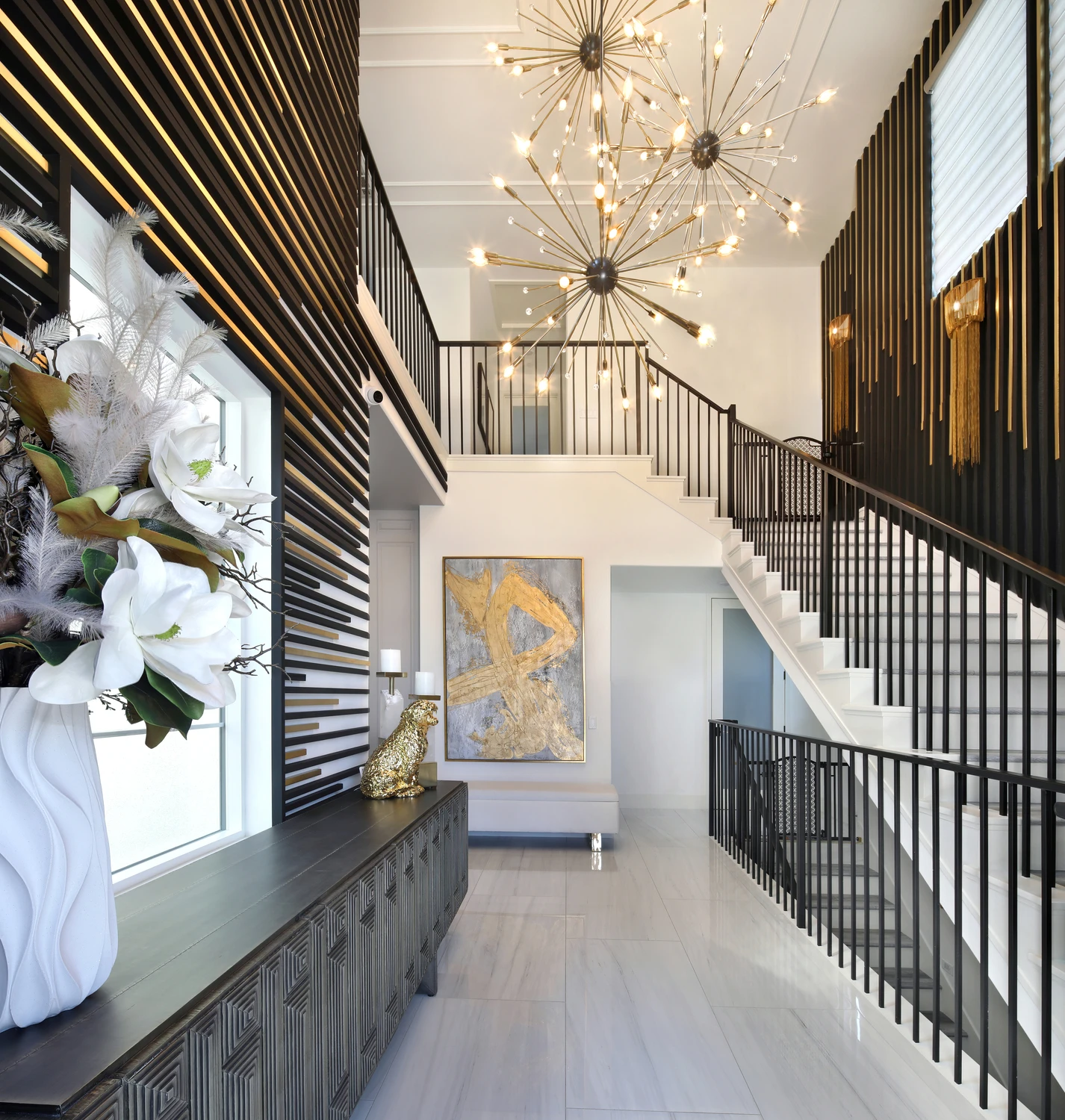 Double-height foyer with black slatted stair wall and chandelier