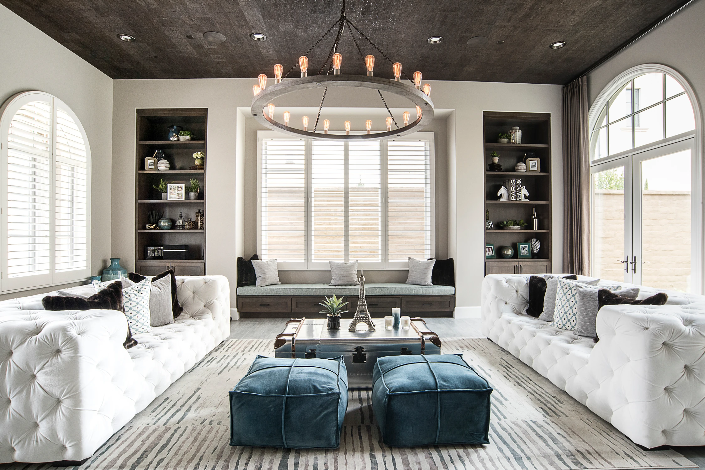 Formal living room with white tufted sofas, black ceiling, and arched windows