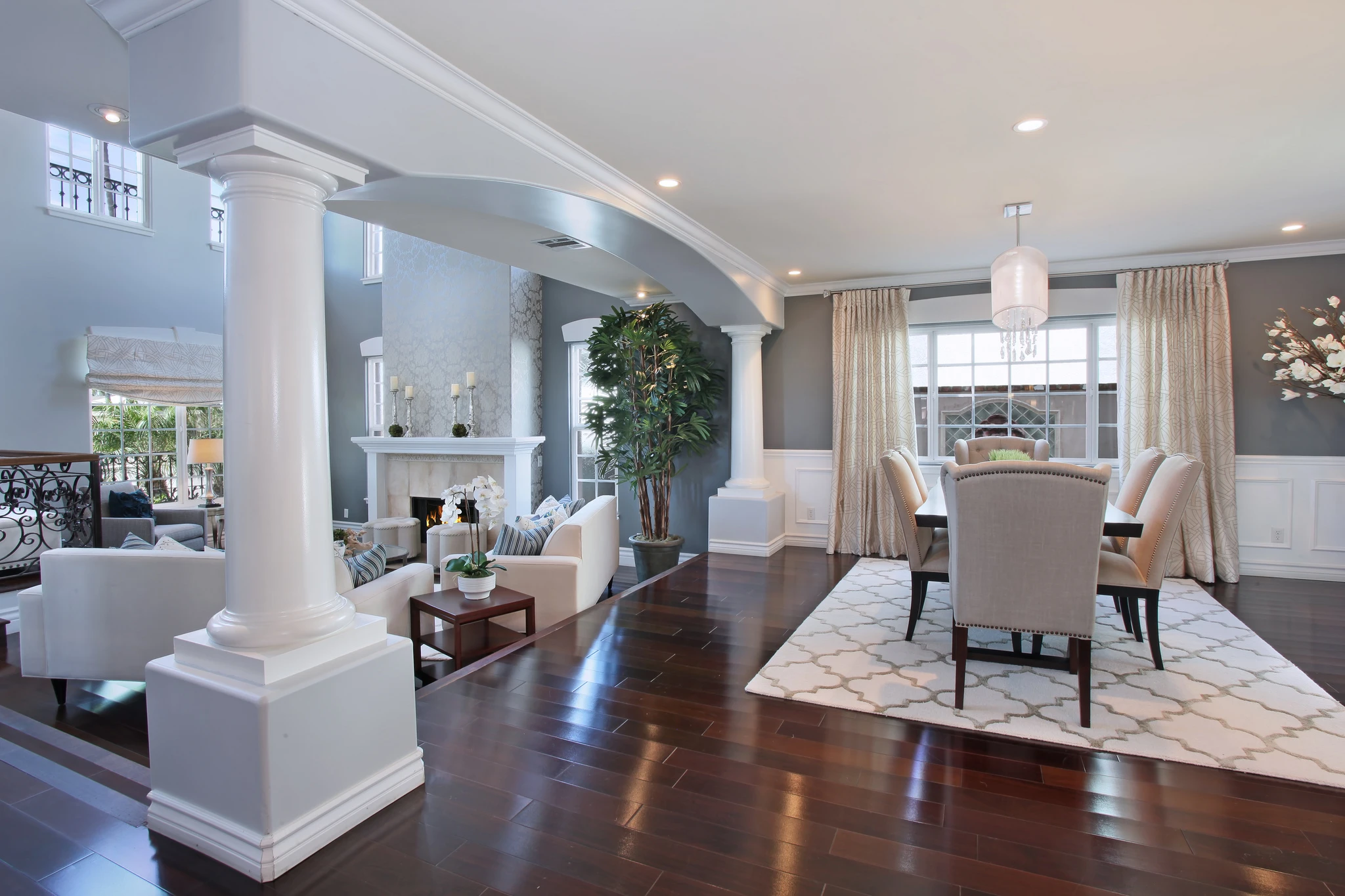 Open living and dining room with white columns and dark wood floor