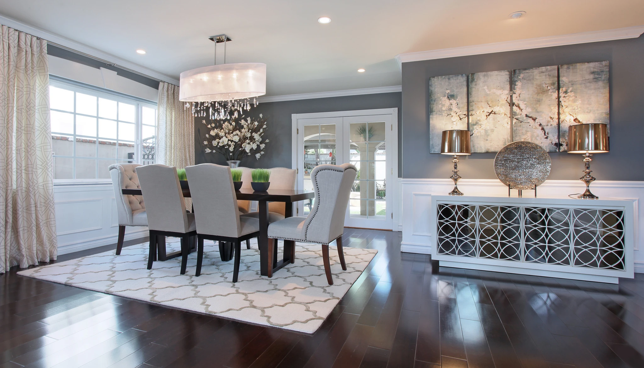 Dining room with gray walls, white chairs, and crystal chandelier