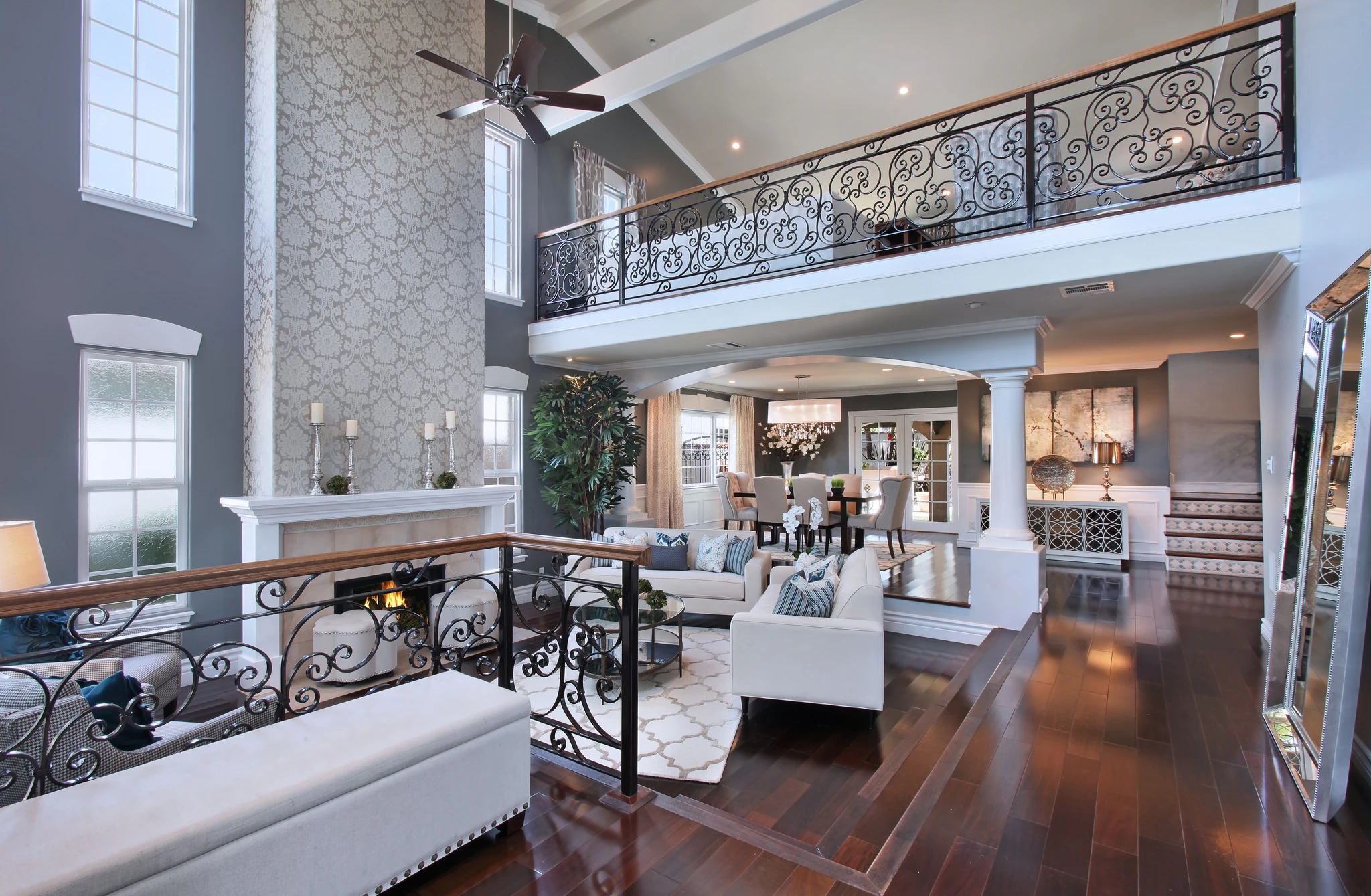 Double-height living room with wrought iron balcony railing and dark wood floor