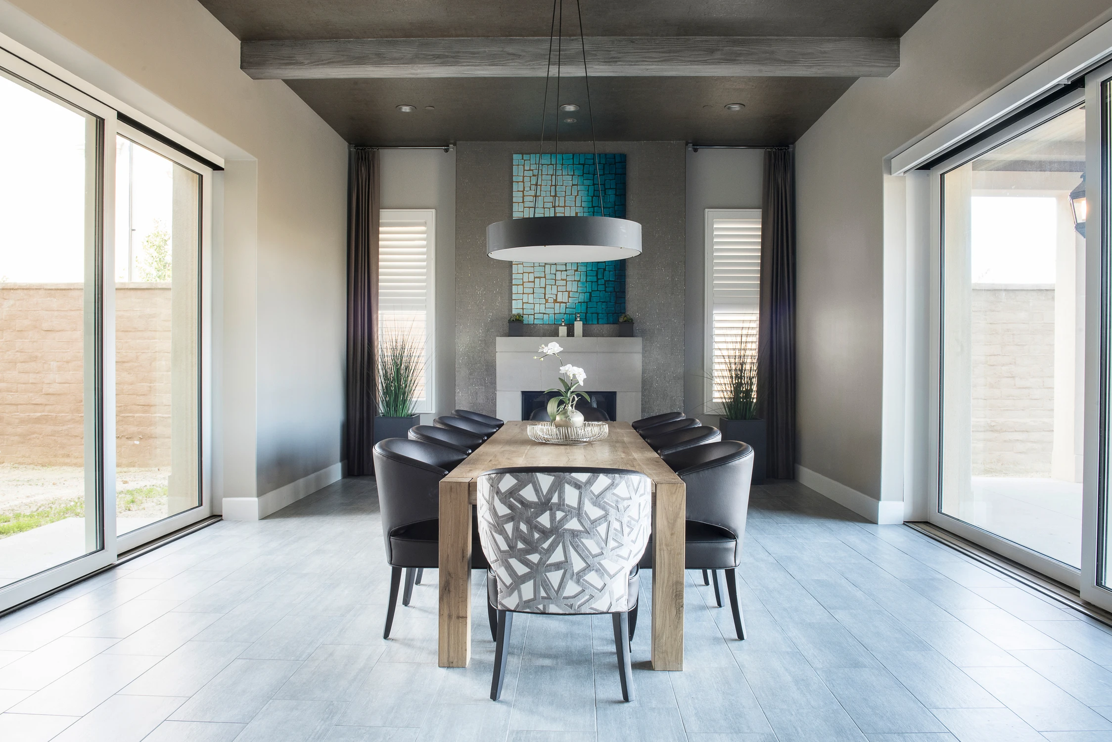 Dining room with dark walls, wood table, and blue artwork