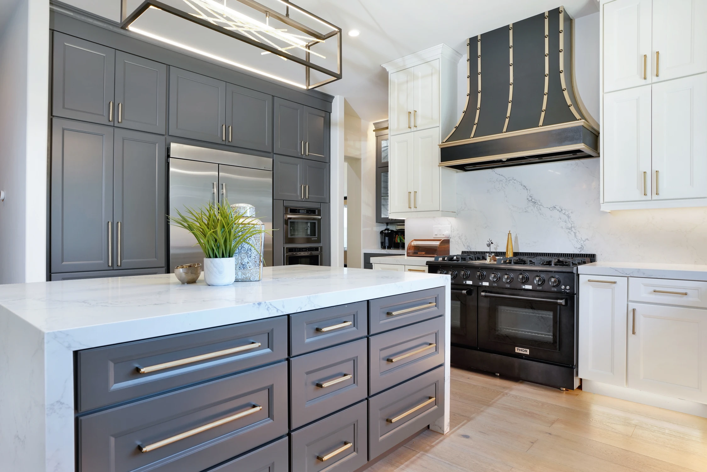 Gray kitchen island with white counter and long brass hardware