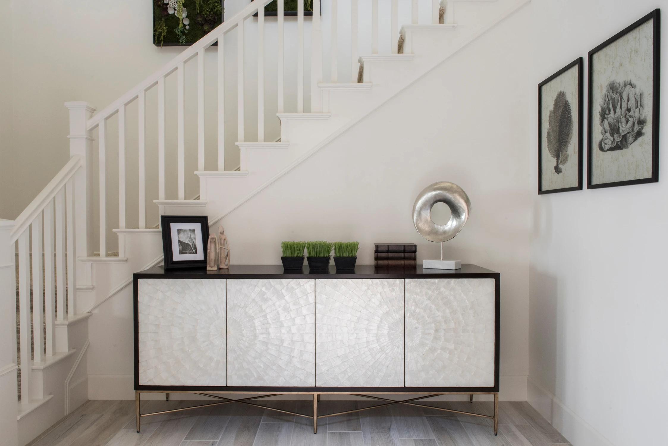 White staircase with console table and framed botanical art