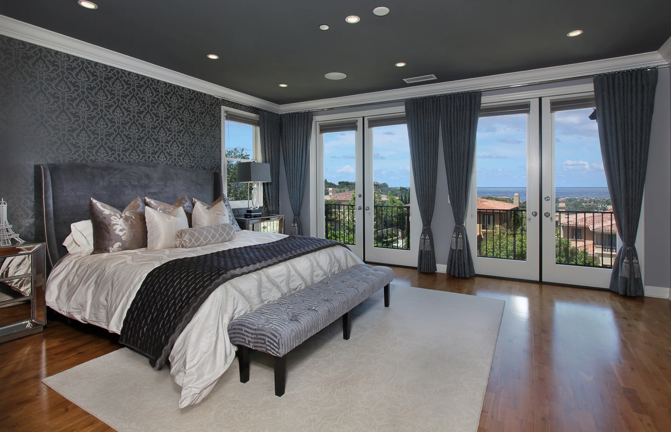 Master bedroom with dark accent wall, upholstered bed, and outdoor view
