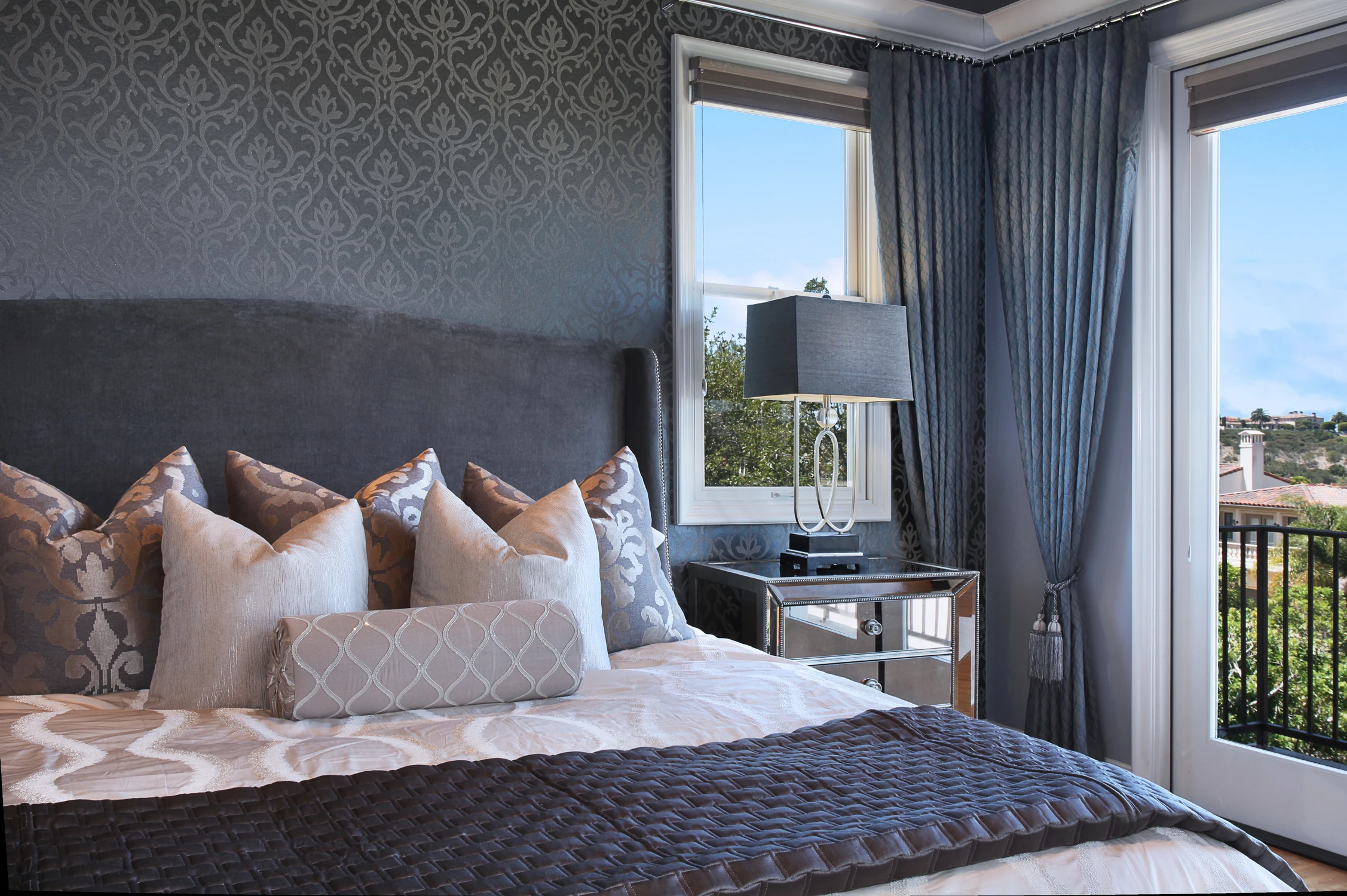 Bedroom with dark patterned wall, white bedding, and balcony view