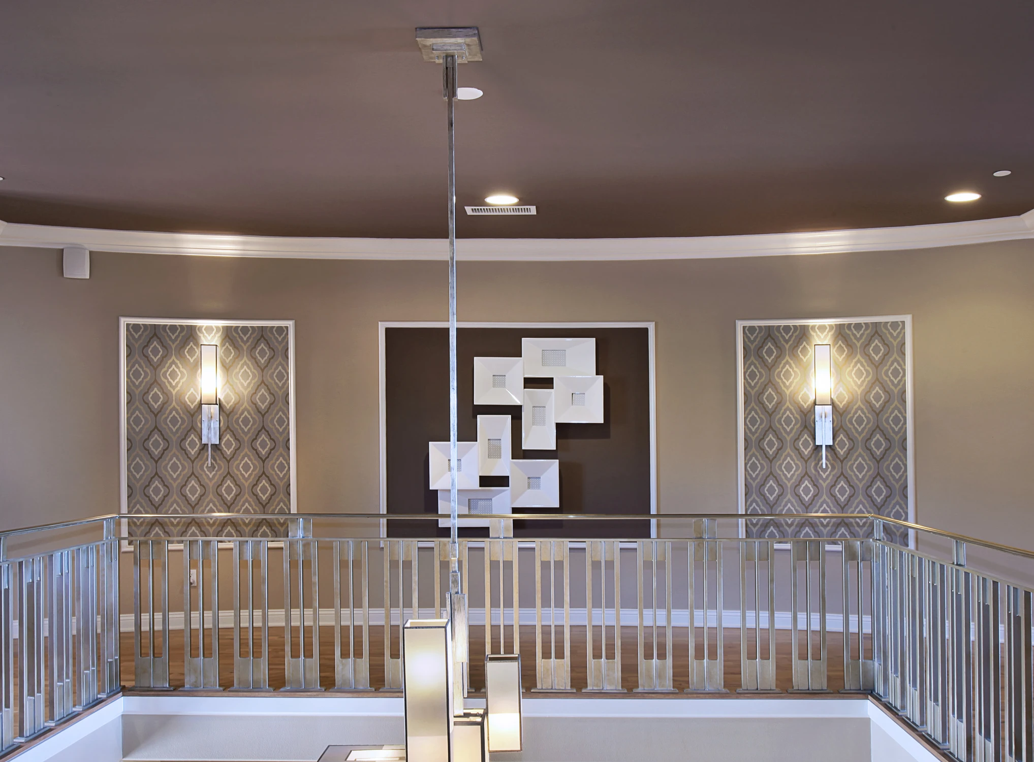 Upper landing with white railing, dark patterned walls, and framed artwork
