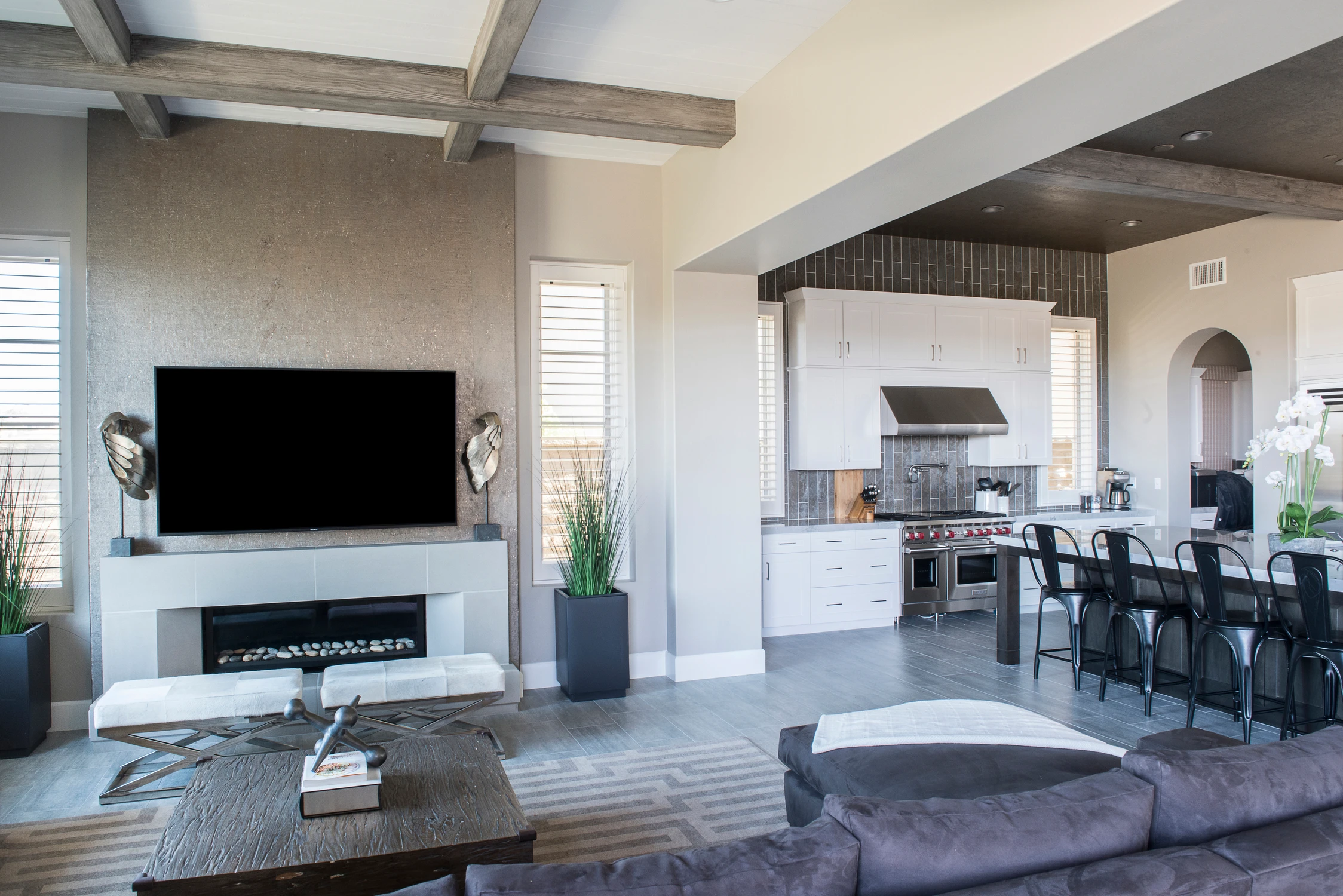 Open family room and kitchen with gray sectional and exposed beams