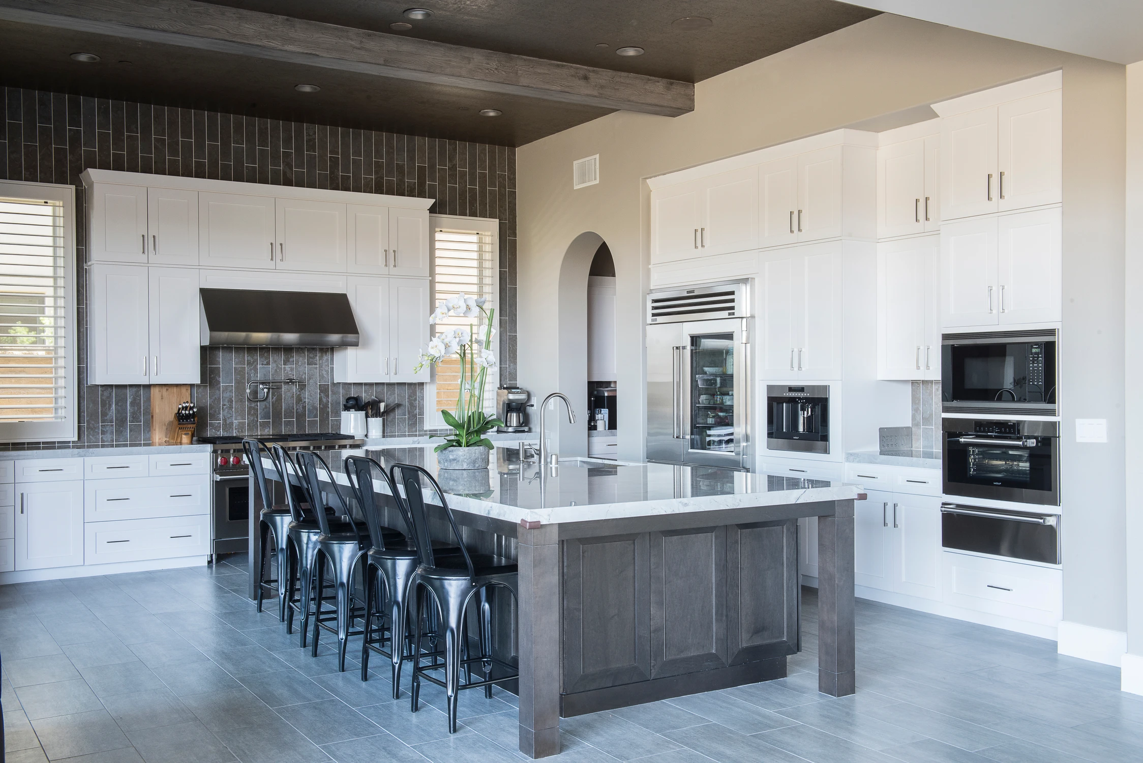 White kitchen with dark island and black bar stools