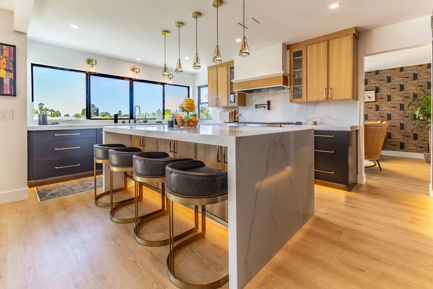 Open kitchen with black island, wood cabinetry, and pendant lights