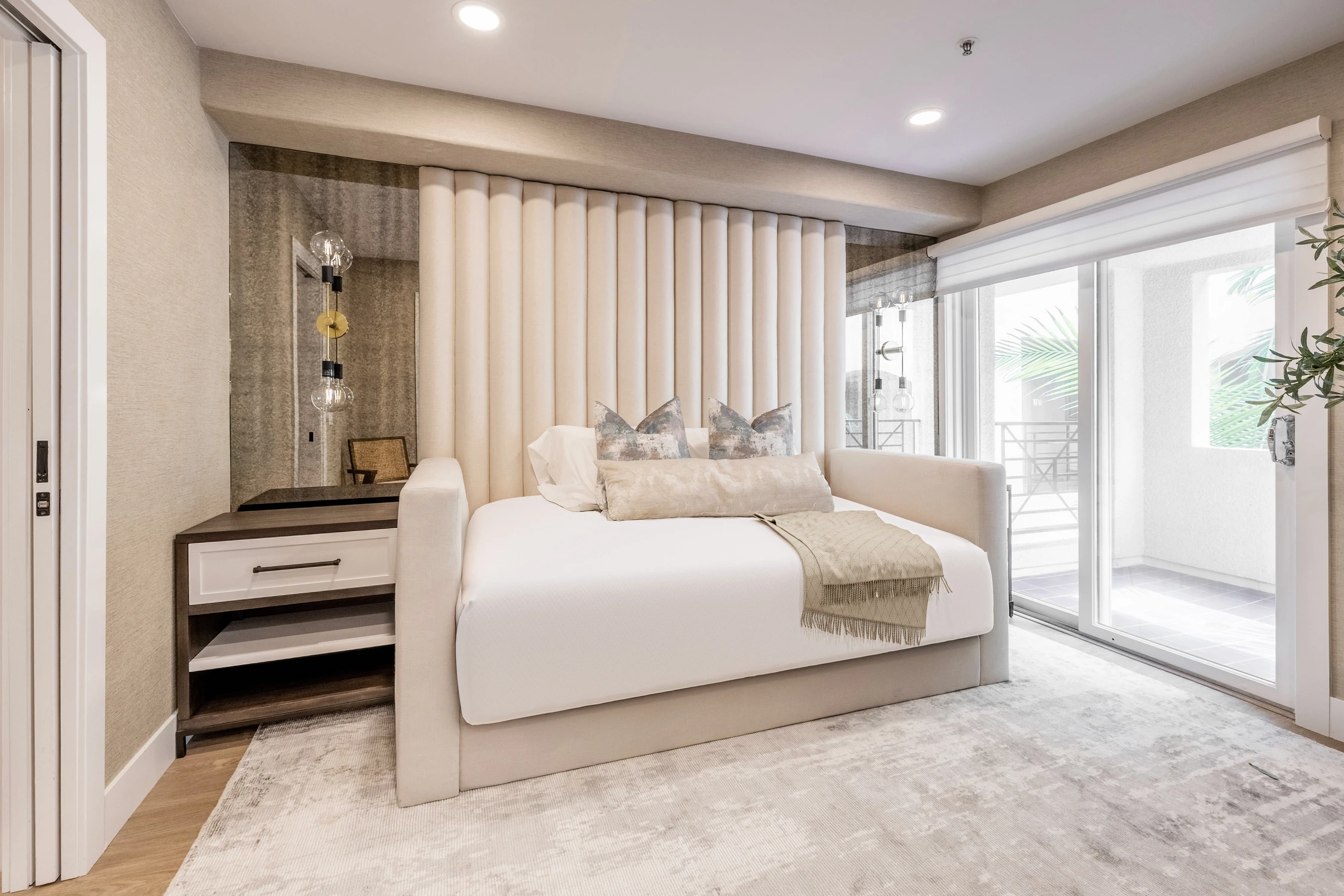 Bedroom with white bed, black floral mural, and sitting chair
