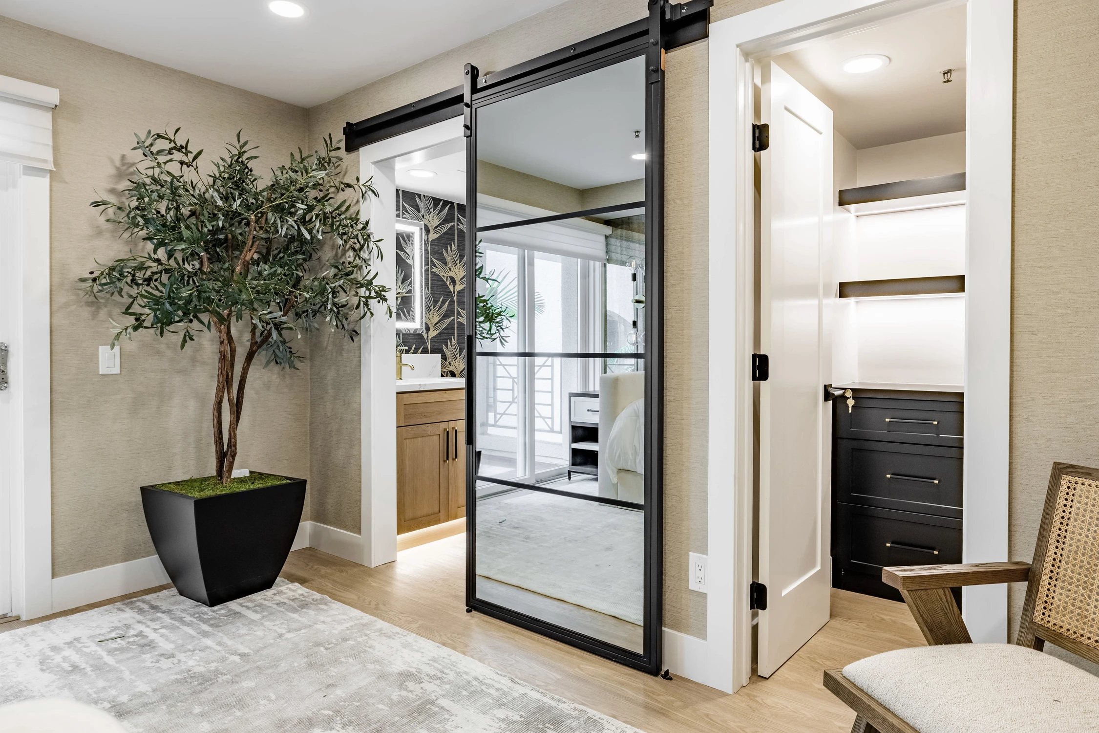 Bedroom entry with black floral mural, mirrored barn door, and white bench