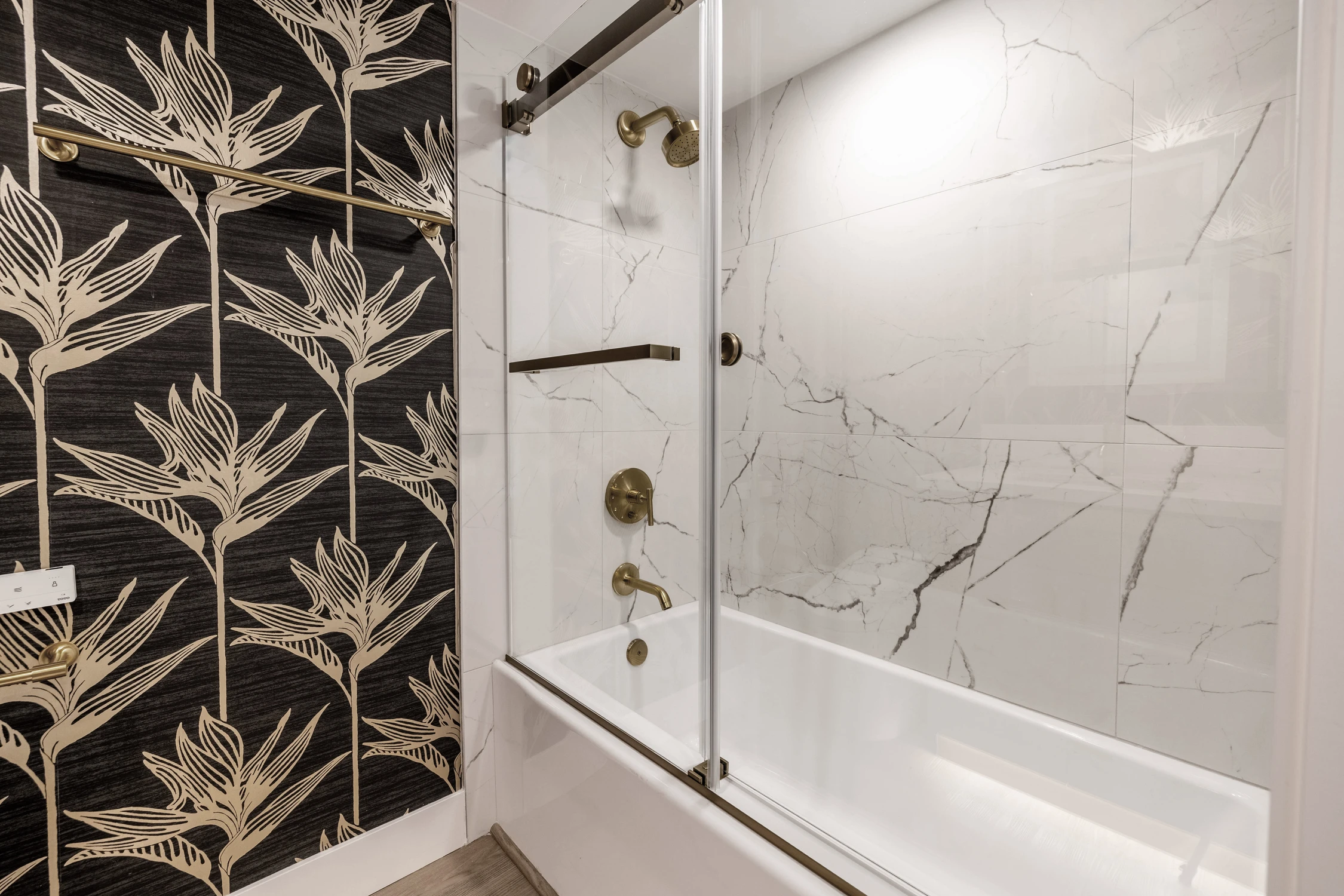 White tiled shower with gold fixtures and glass enclosure