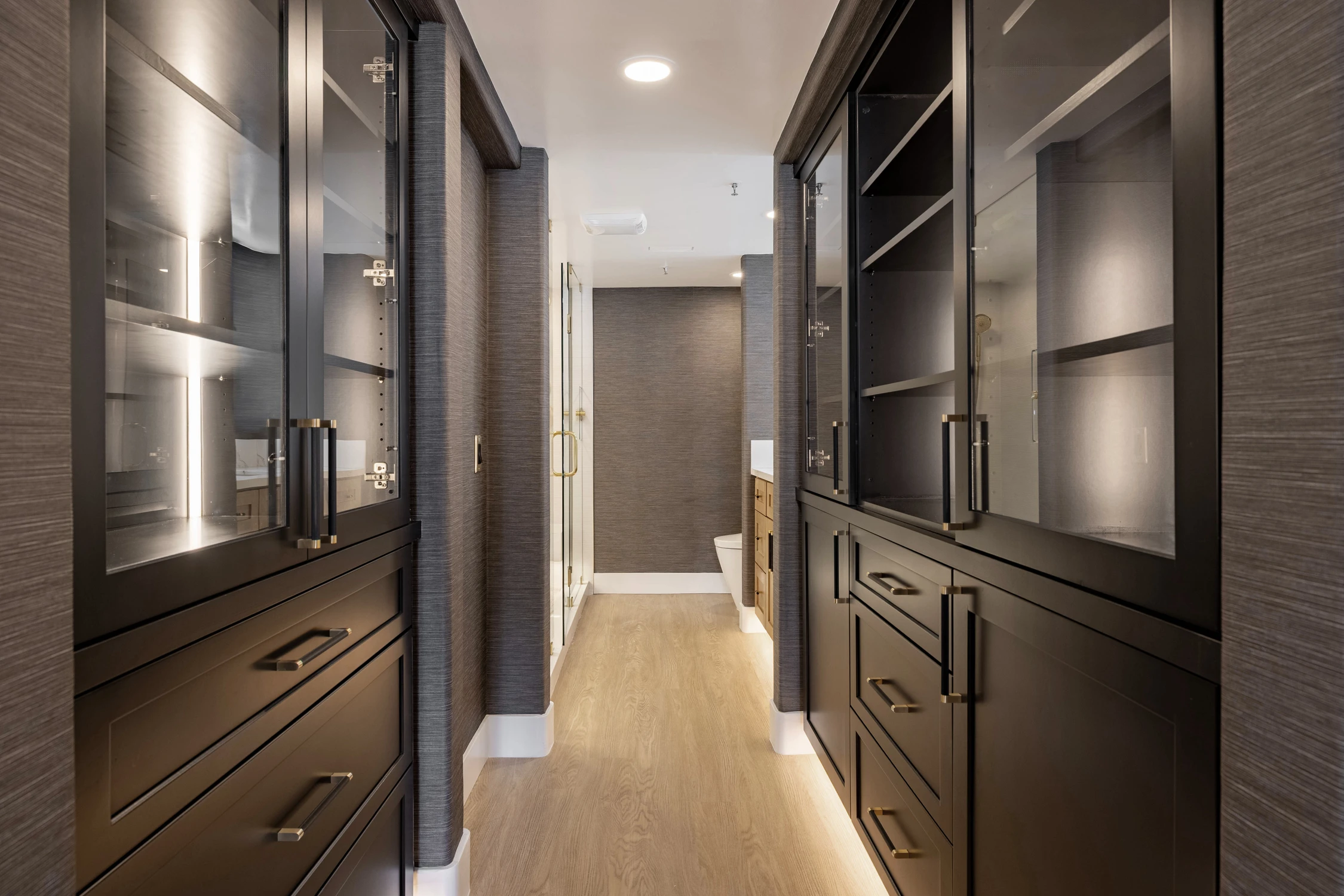Walk-in closet with mirrored wardrobe doors and wood floor