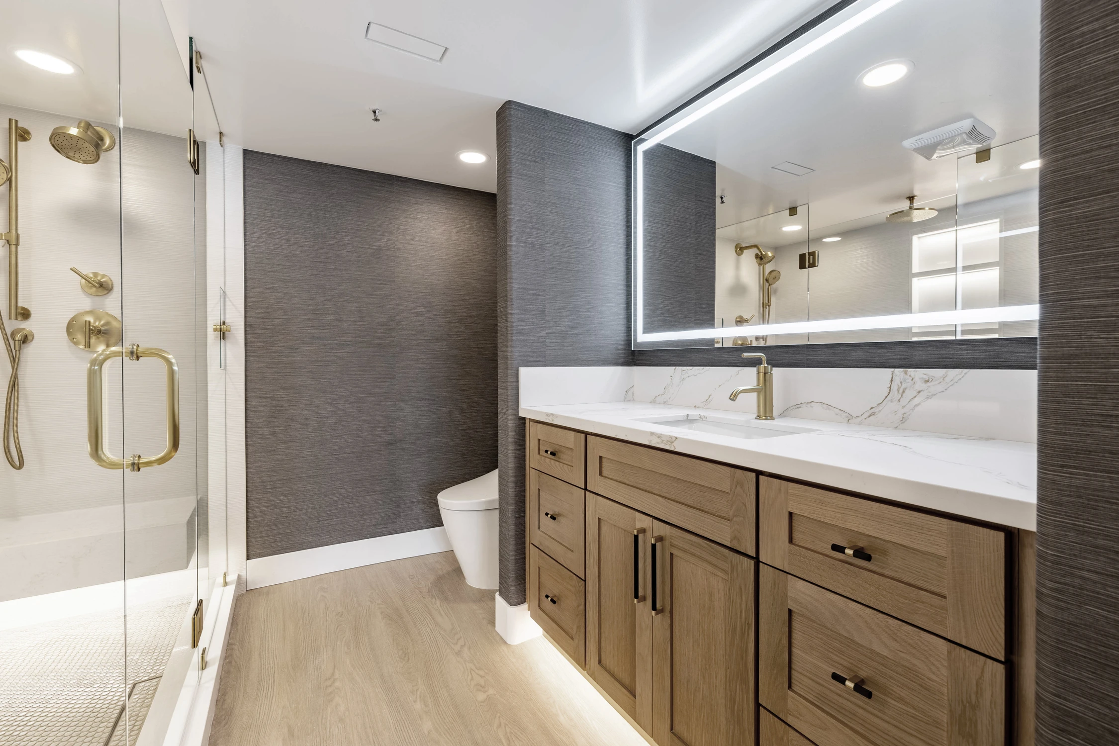 Glass shower with white tile and gold fixtures