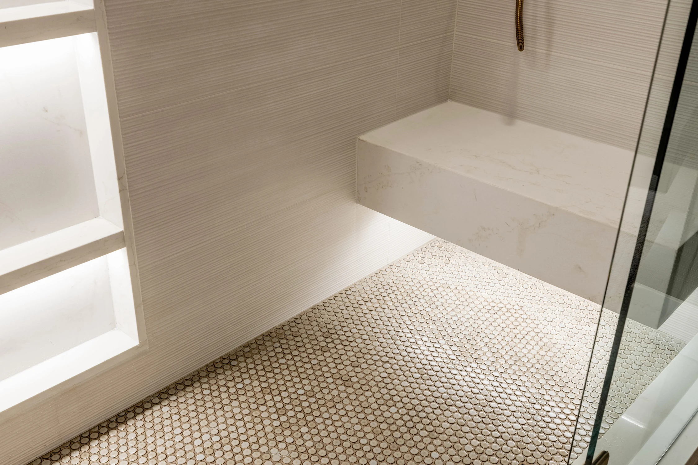 Gold shower control on white marble-look tile