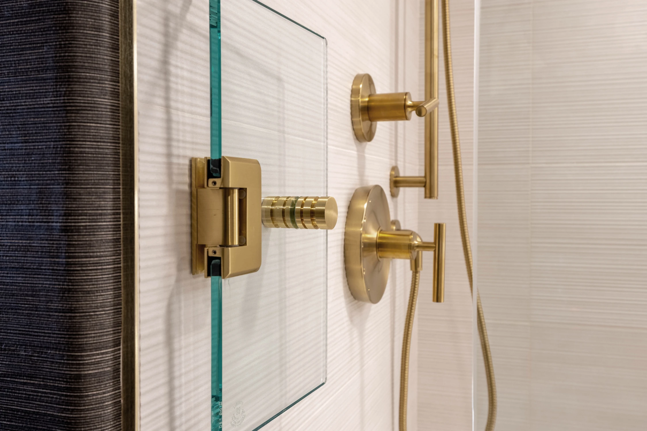 Glass shower enclosure with white tile and gold hardware