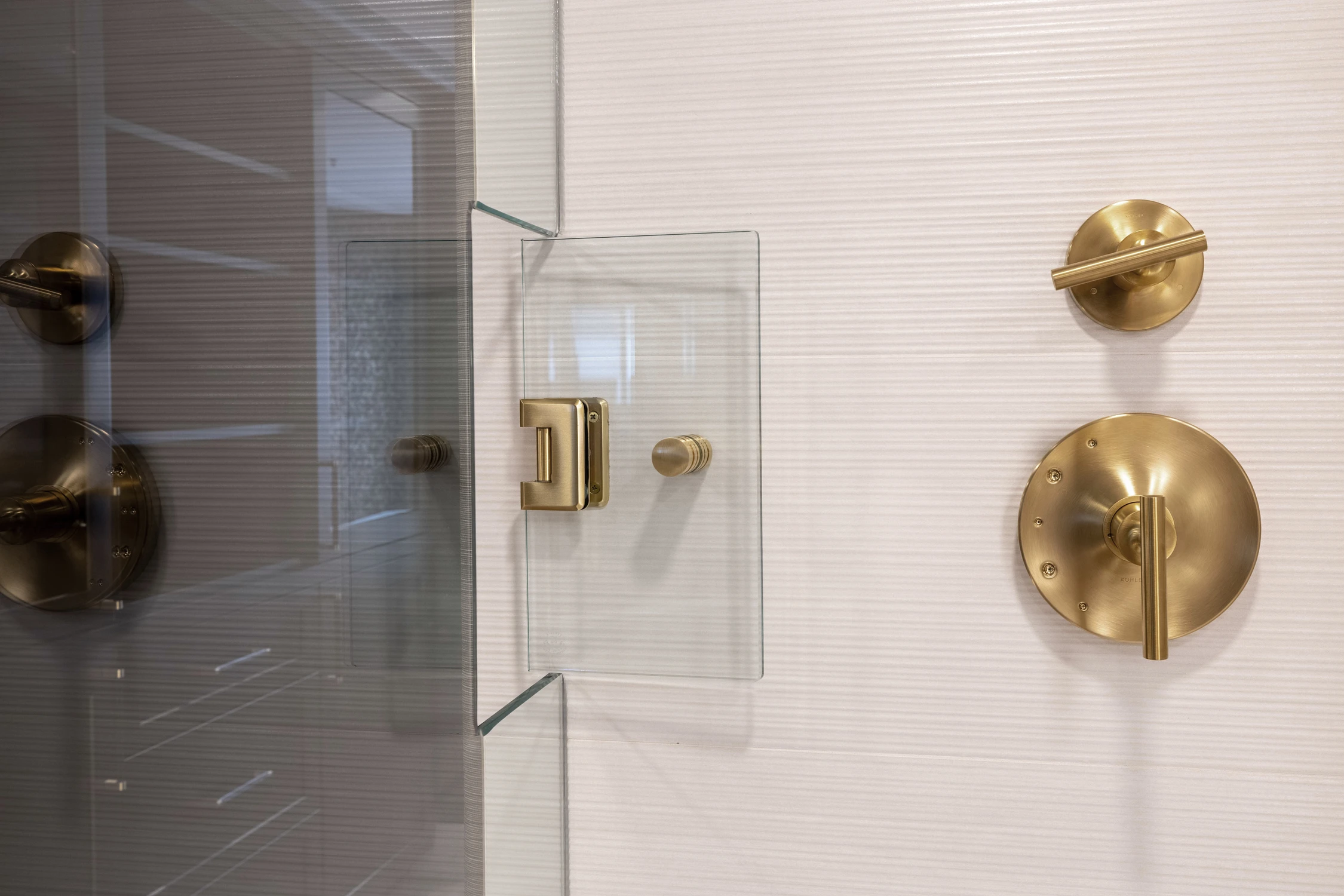 Close view of glass shower door and brushed gold controls