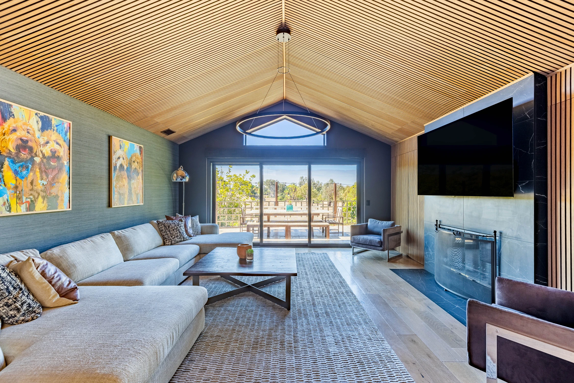 Living room with vaulted wood ceiling and expansive rear windows