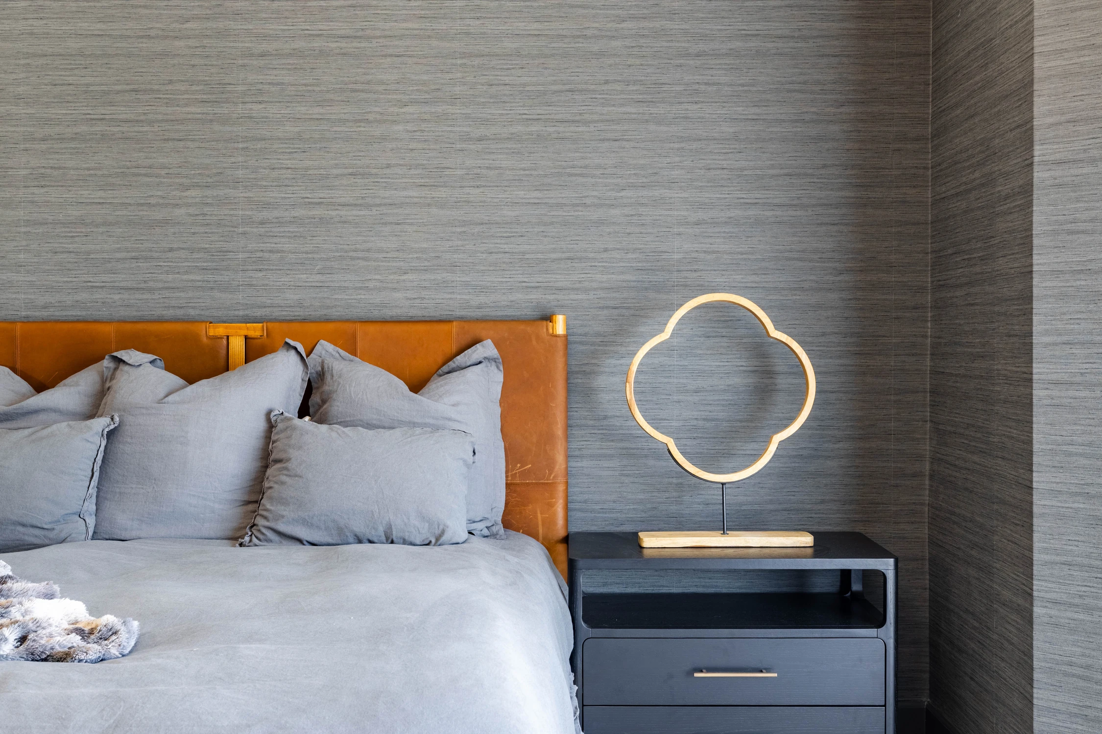 Bedroom with warm wood headboard and circular wall sconces