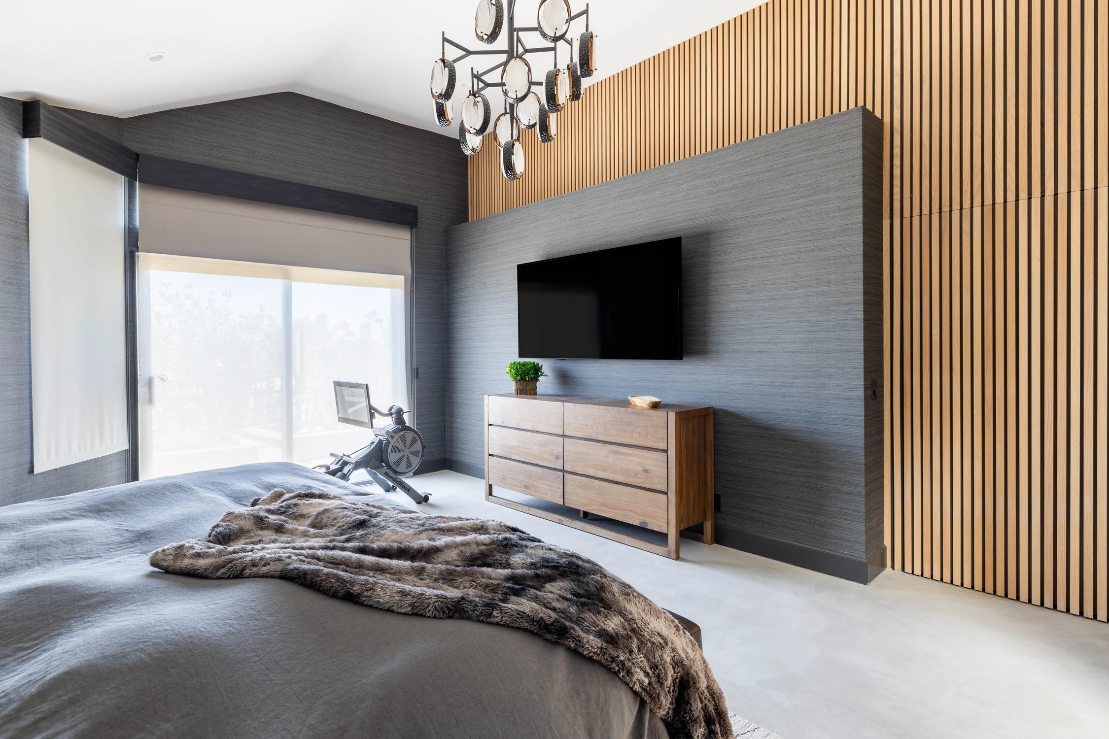 Bedroom with textured dark wall panel and low wood dresser