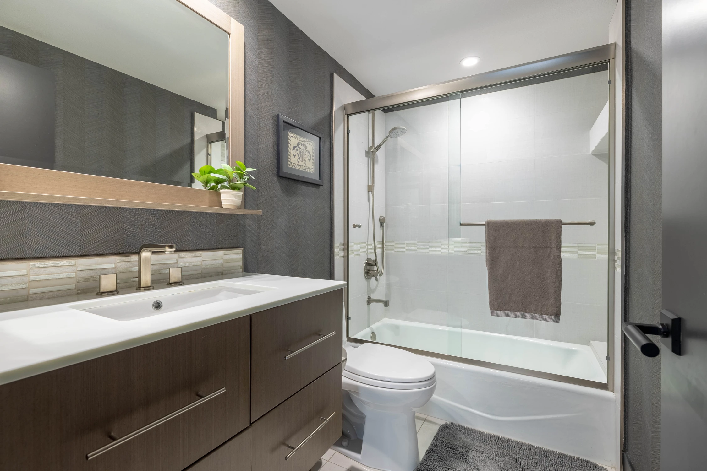 Bathroom with dark floating vanity, glass shower, and white tub