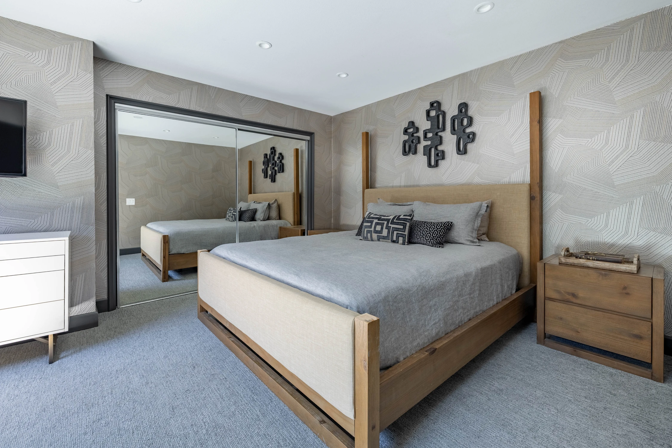 Bedroom with pale wood bed frame and white patterned feature wall