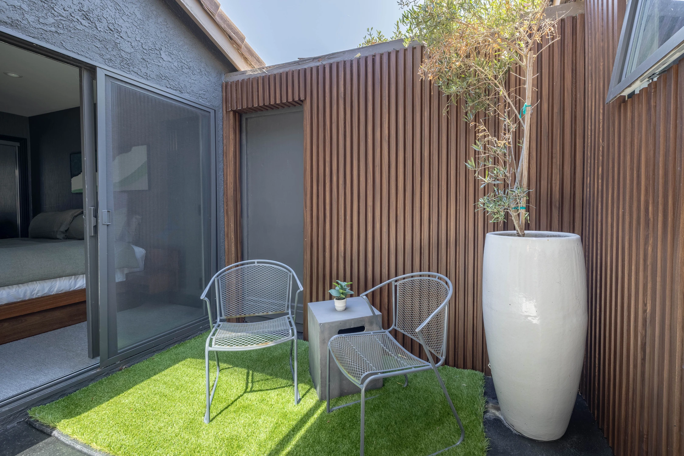 Small outdoor sitting area beside wood slat siding and artificial turf