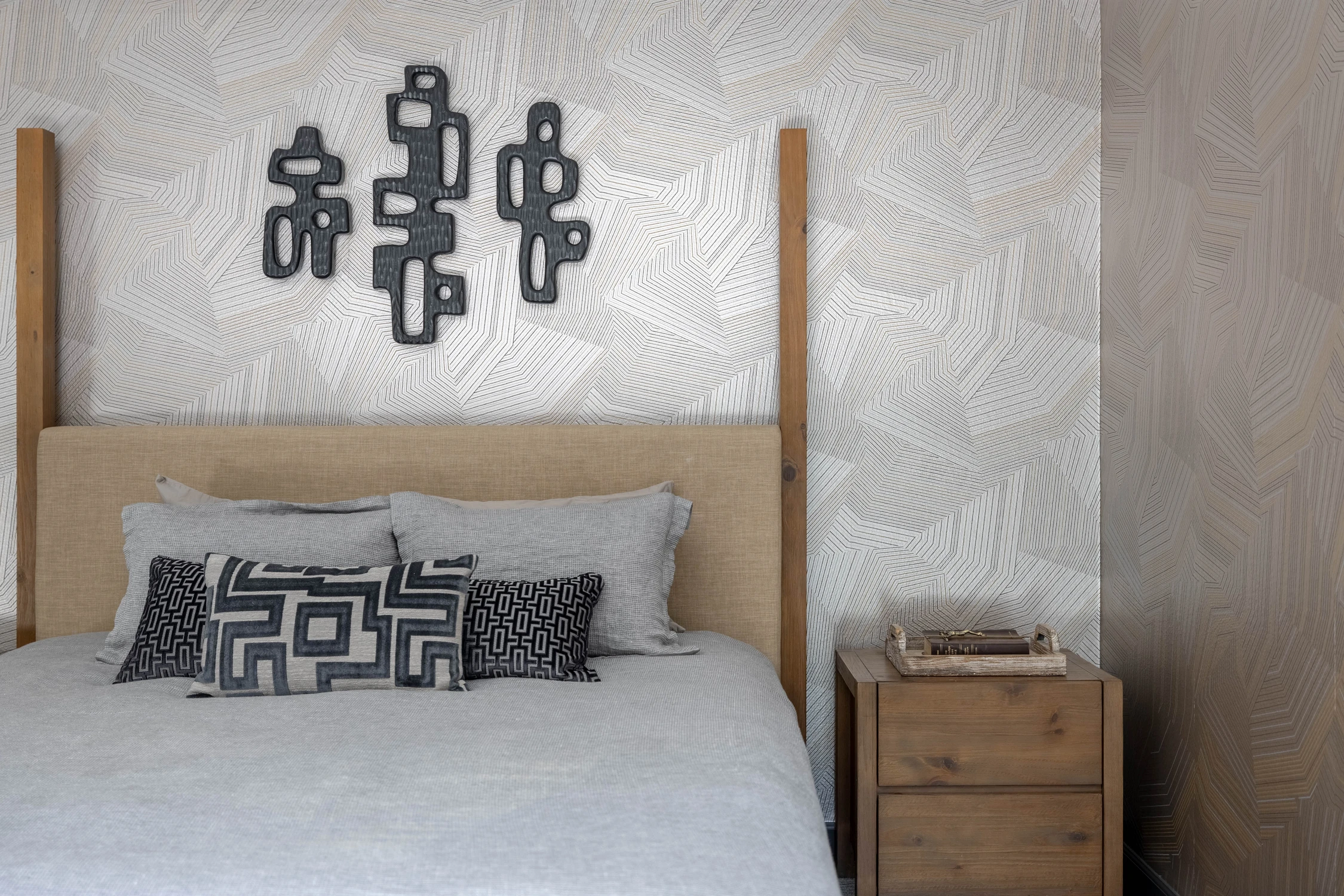 Bedroom with wood slat headboard wall and black geometric artwork