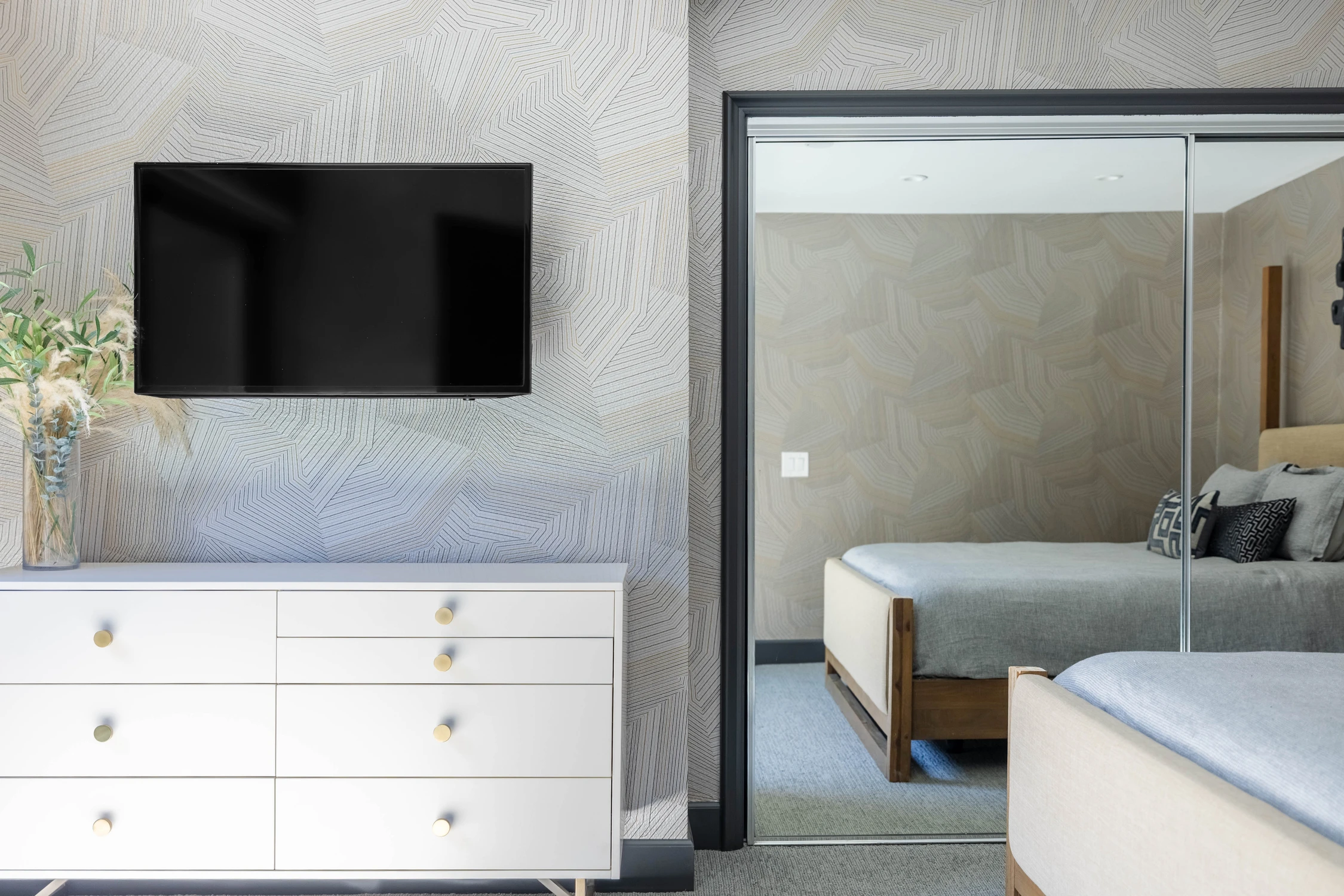 Bedroom media wall with white dresser and dark framed opening