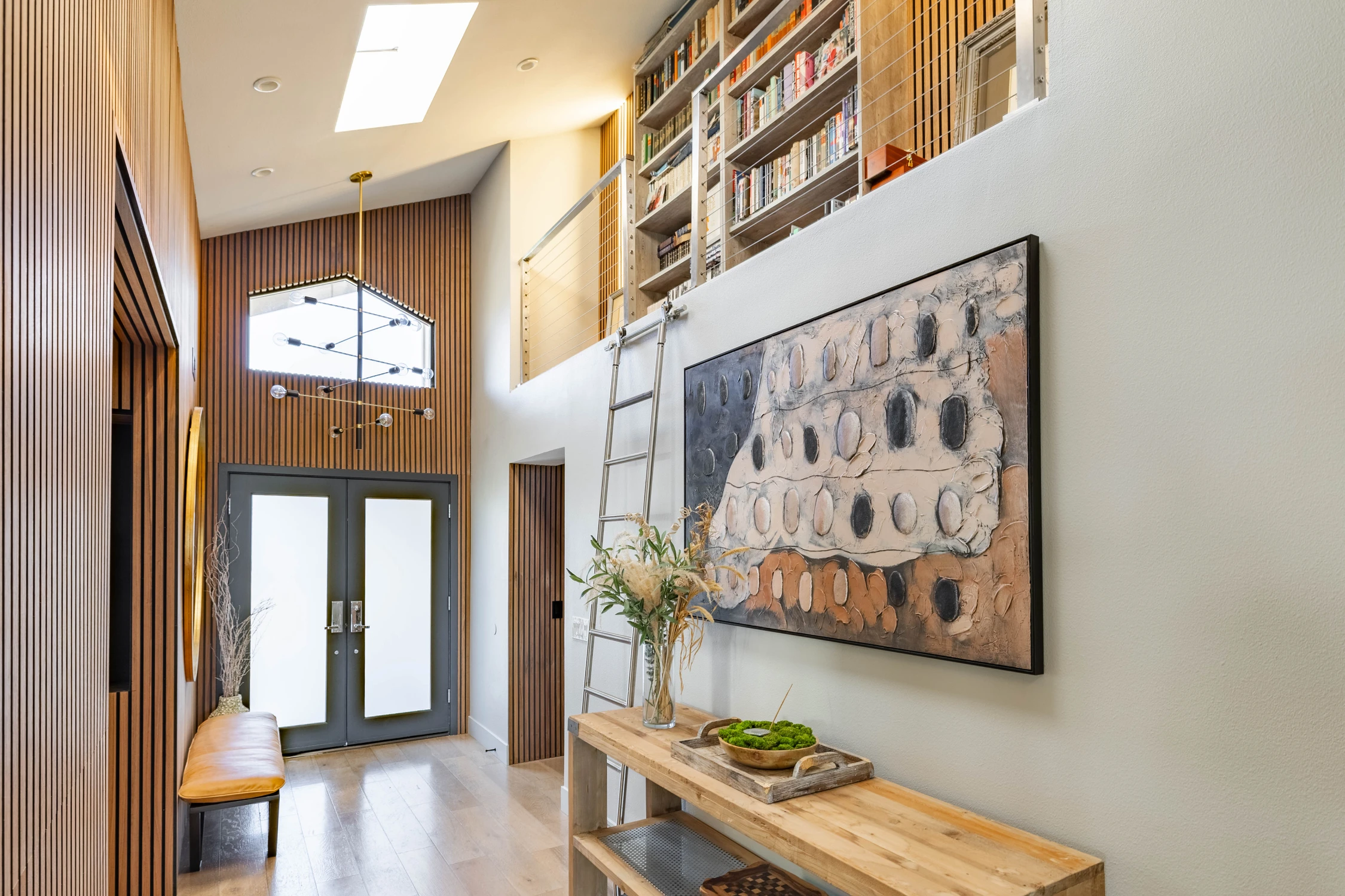 Double-height entryway with wood slat walls and sculptural chandelier
