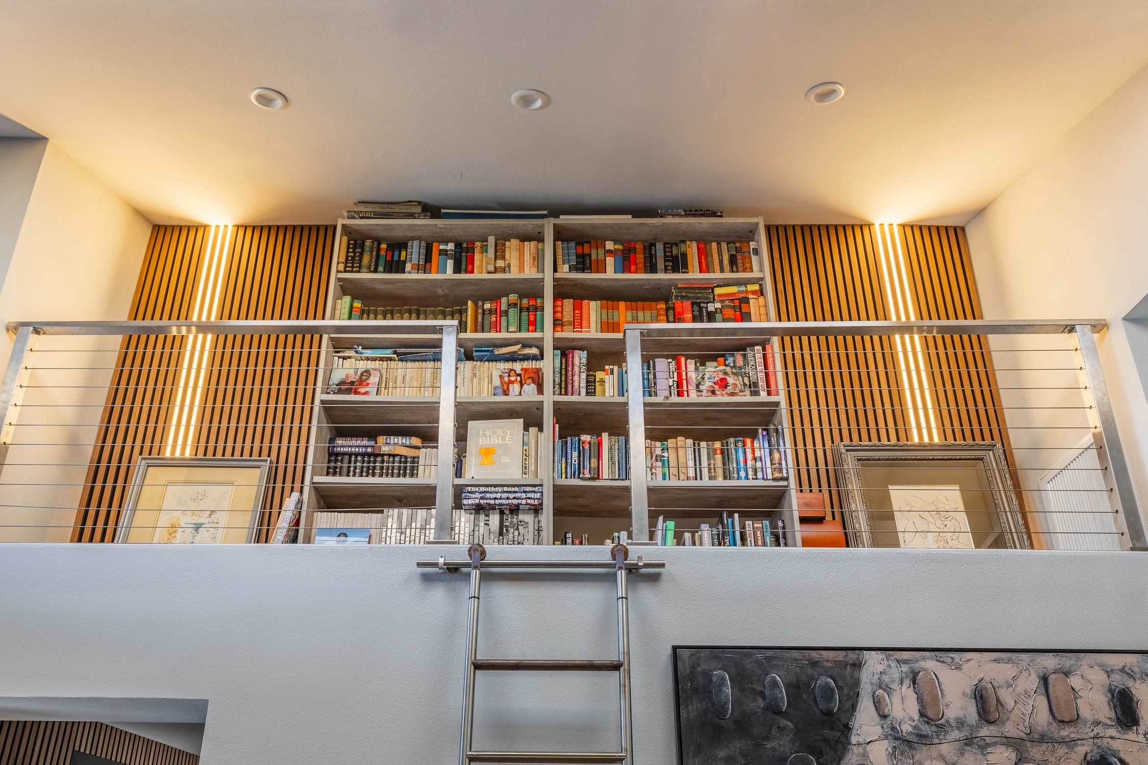 Loft library with illuminated bookshelves and rolling ladder