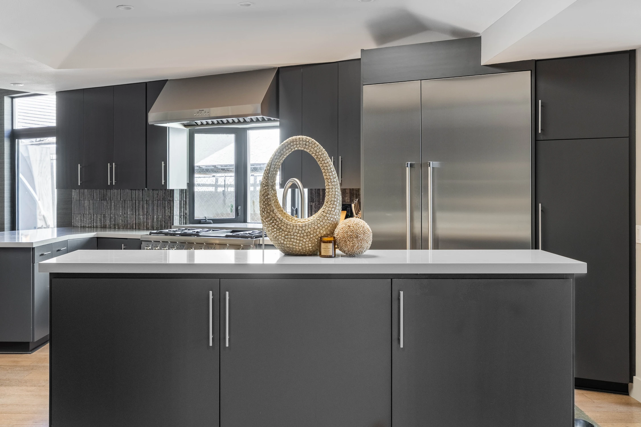 Charcoal kitchen cabinetry with a long white waterfall island