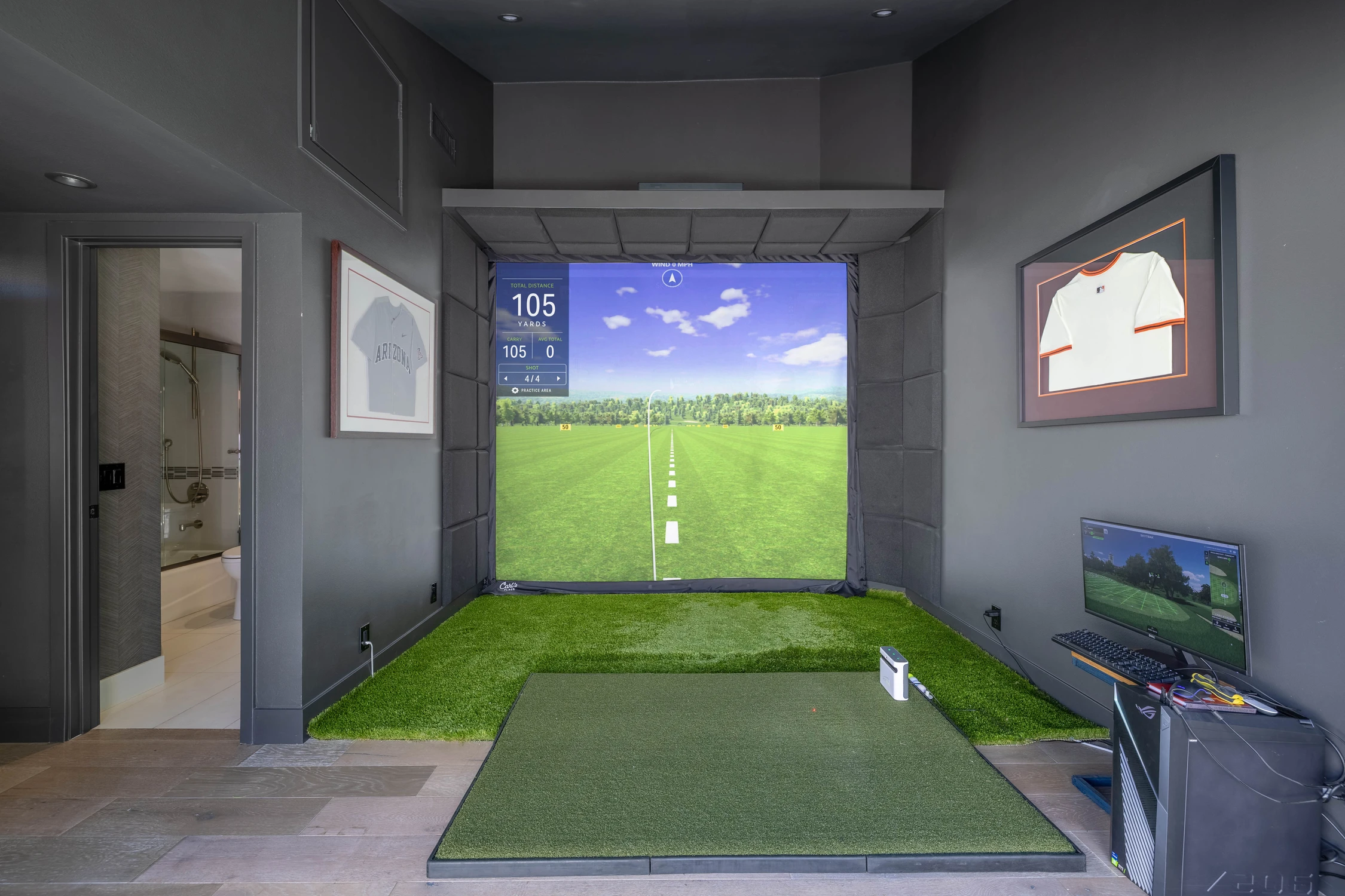 Golf simulator room with indoor golf screen and green turf floor