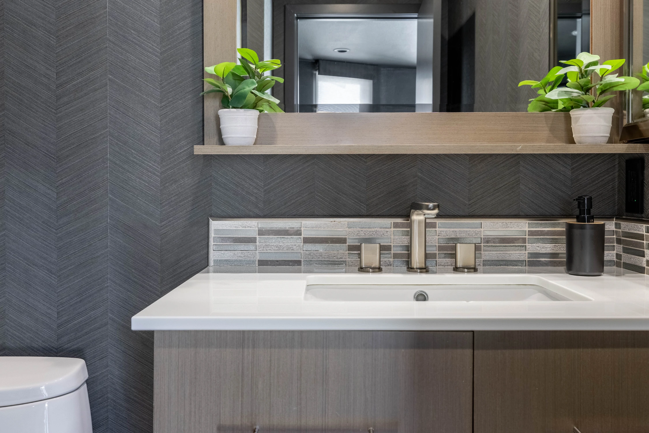 Bathroom vanity with black-framed mirror and gray geometric tile