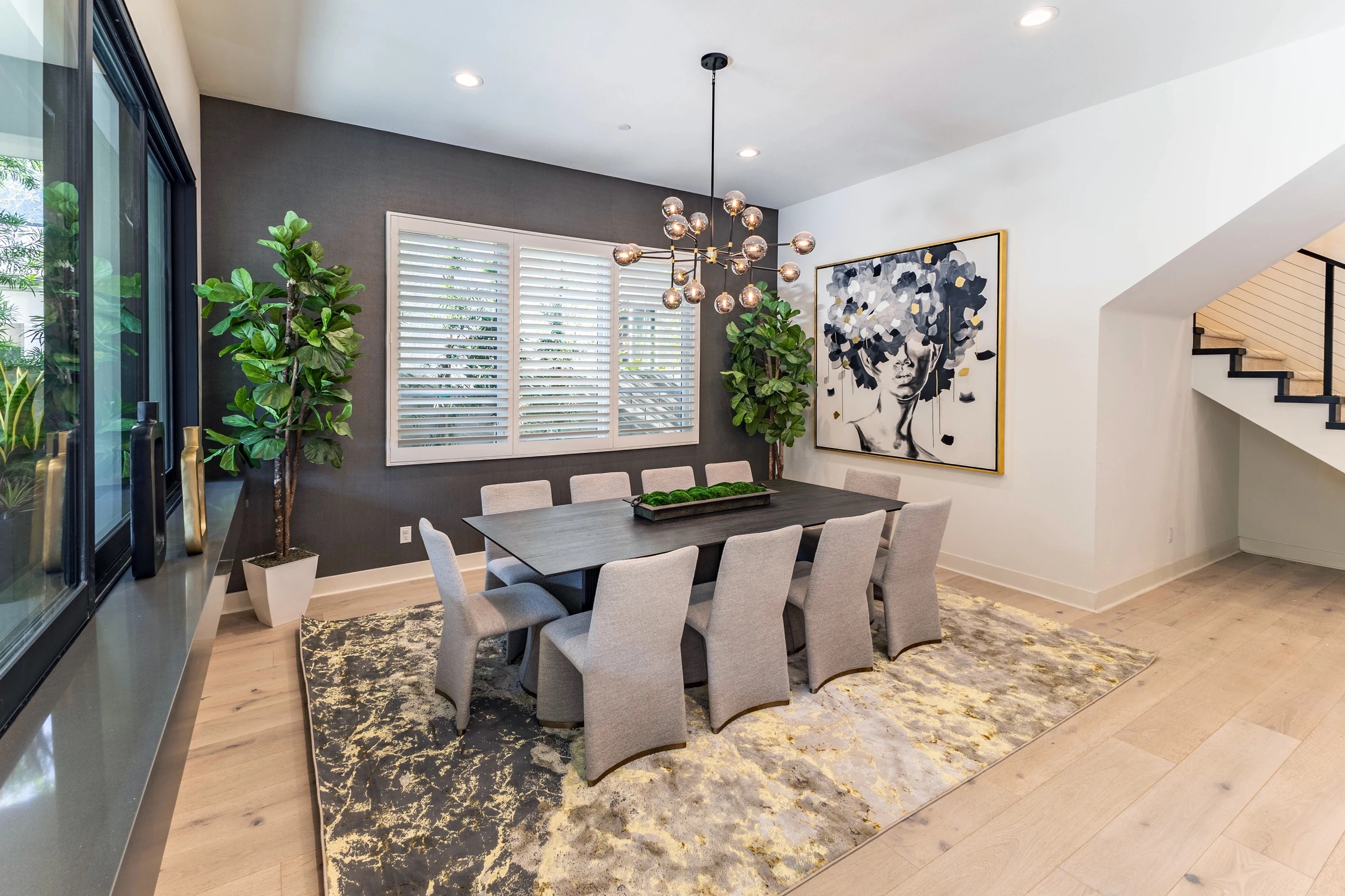Dining room with upholstered chairs, branching chandelier, and portrait artwork