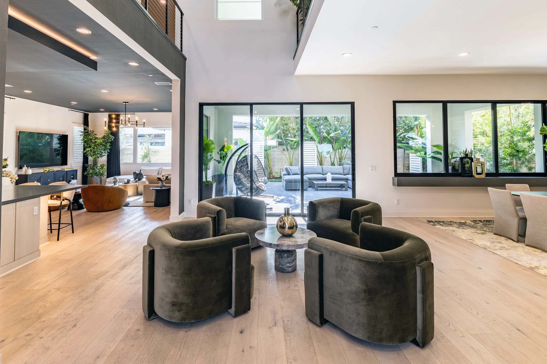 Sitting area with dark green barrel chairs, black table, and garden doors