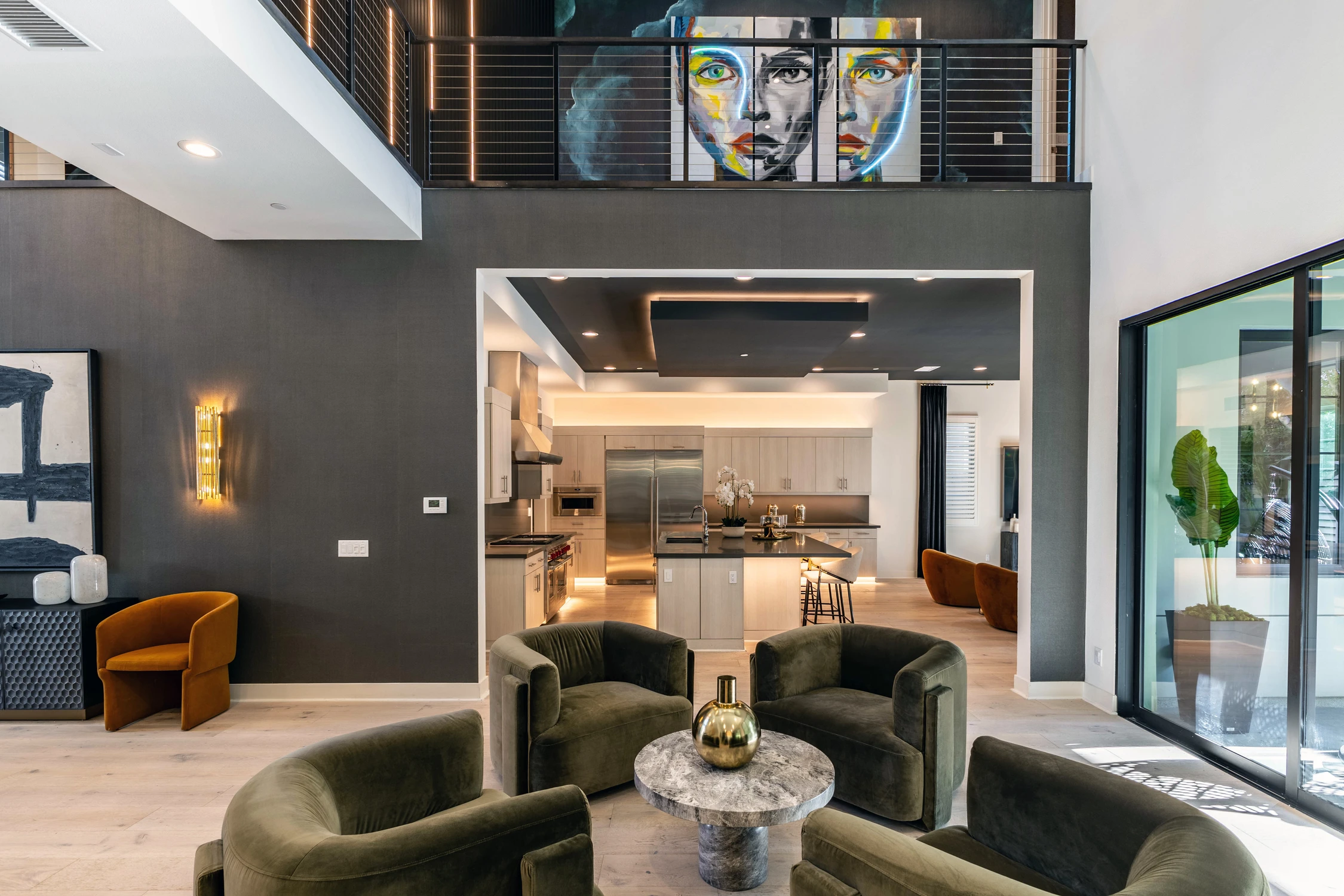 Open living area with dark green chairs, kitchen, and dining room