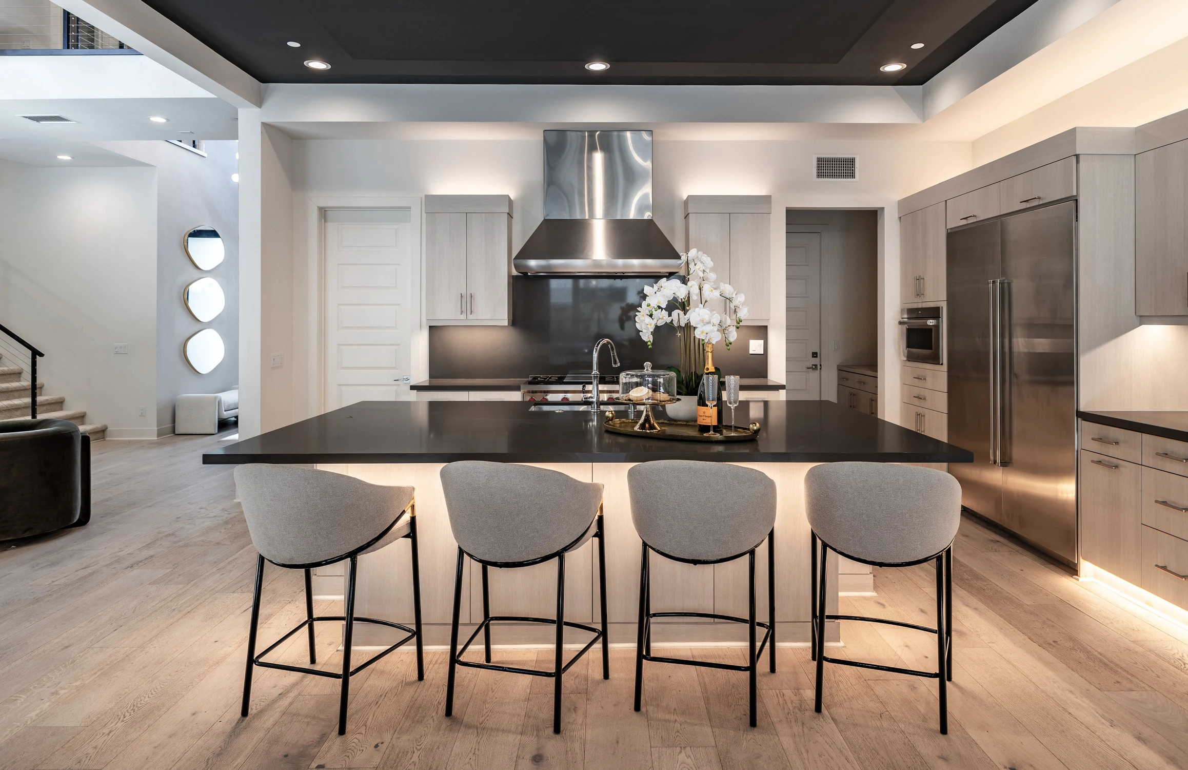 Kitchen with black island, stainless range, and pale wood cabinetry