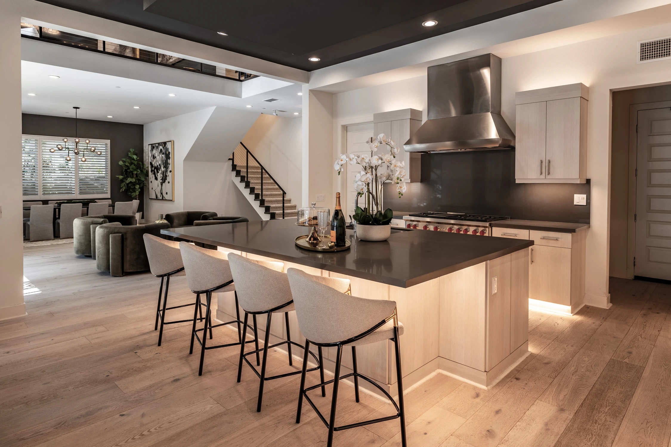 Kitchen island with pale stools, black counter, and stainless range