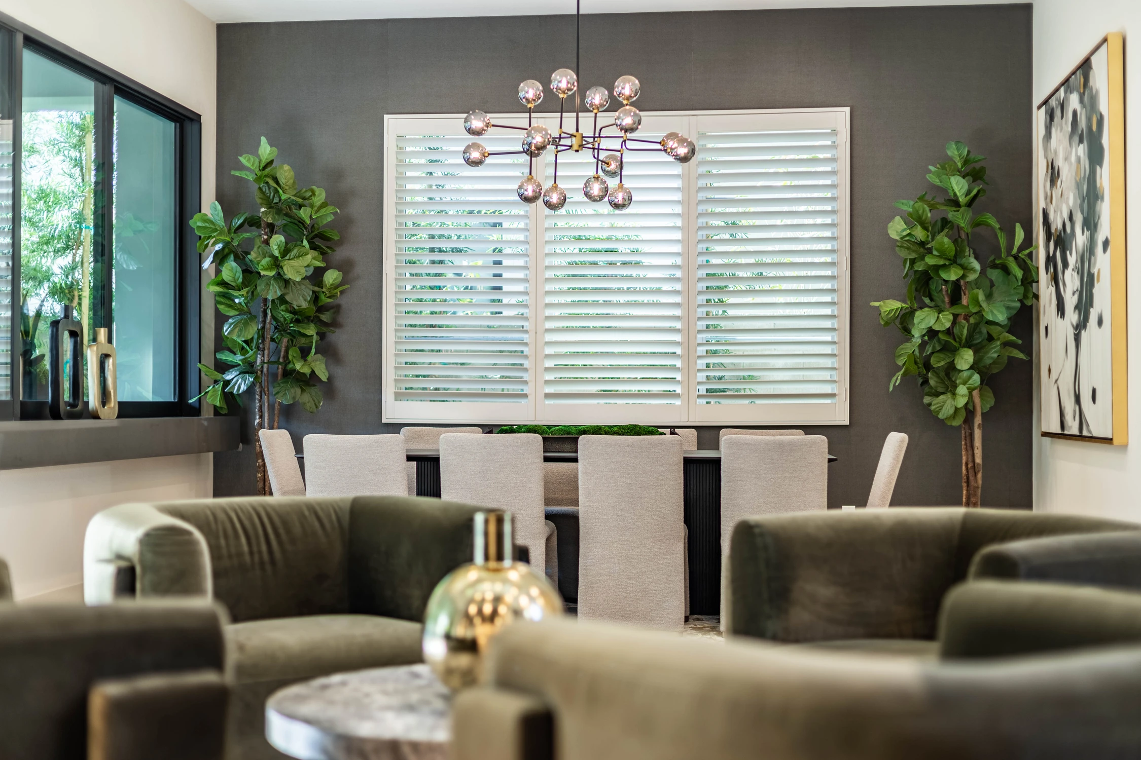 Dining table beneath glass globe chandelier and dark accent wall