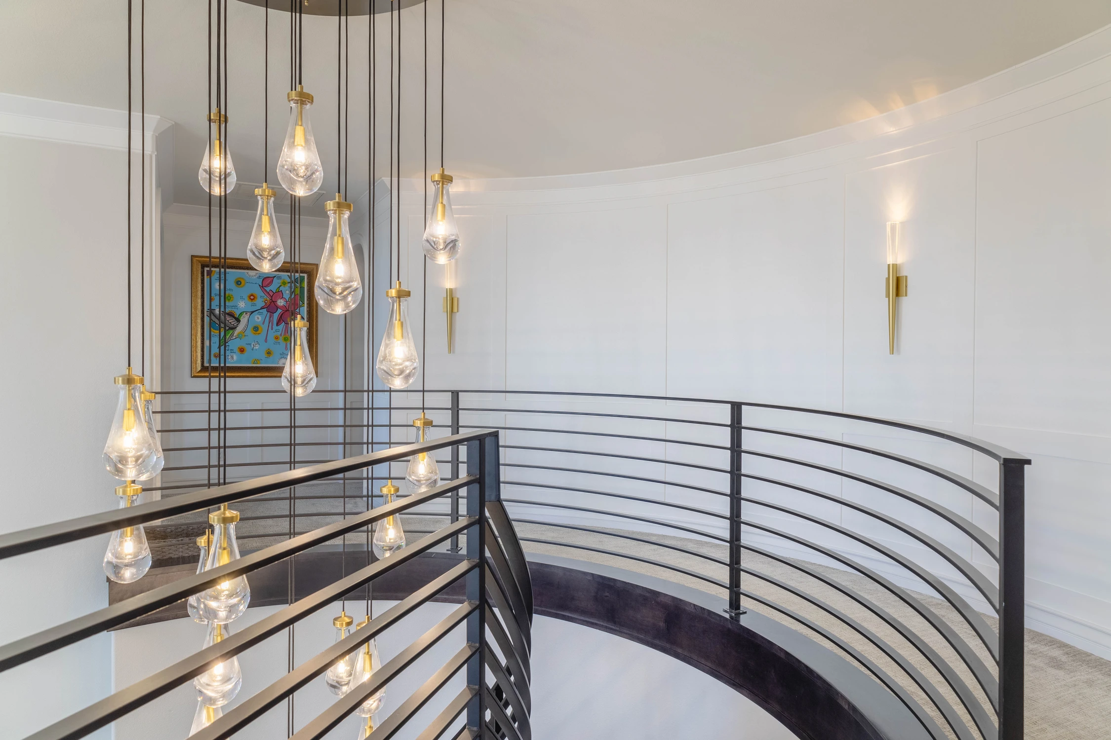 Curved stair landing with black railing and cascading pendants