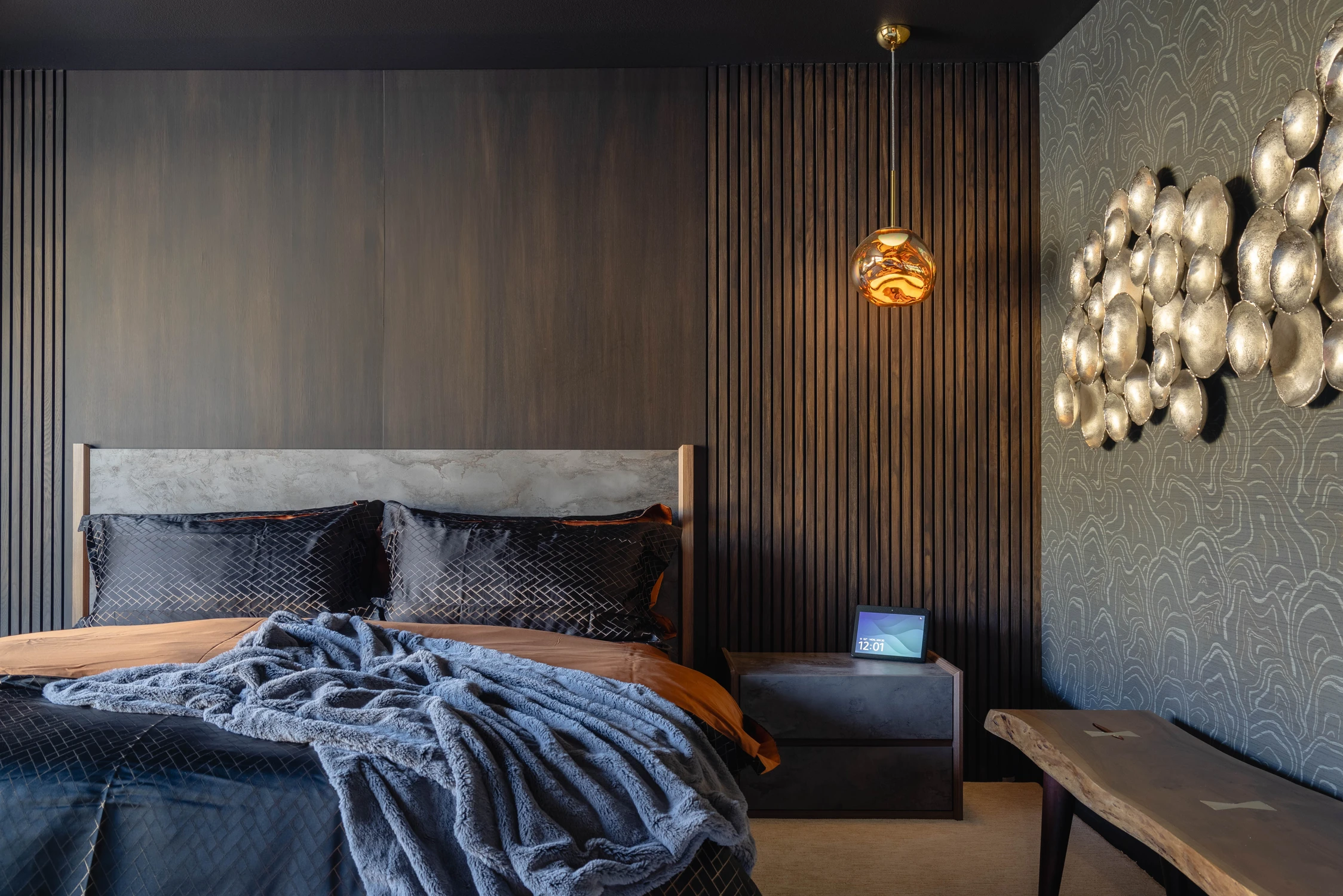 Dark bedroom with vertical wood panels and metallic wall sculpture
