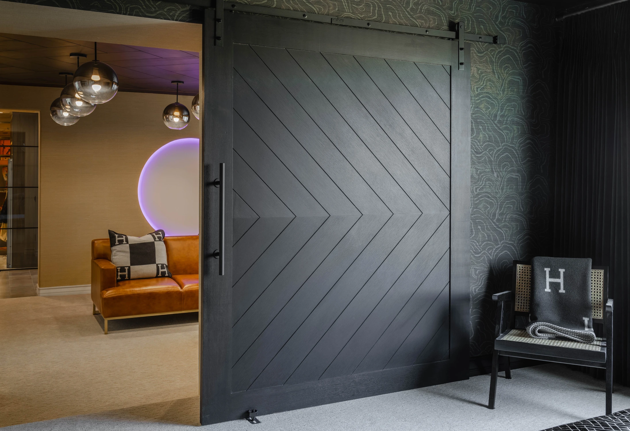 Dark bedroom with sliding door opening to orange leather lounge