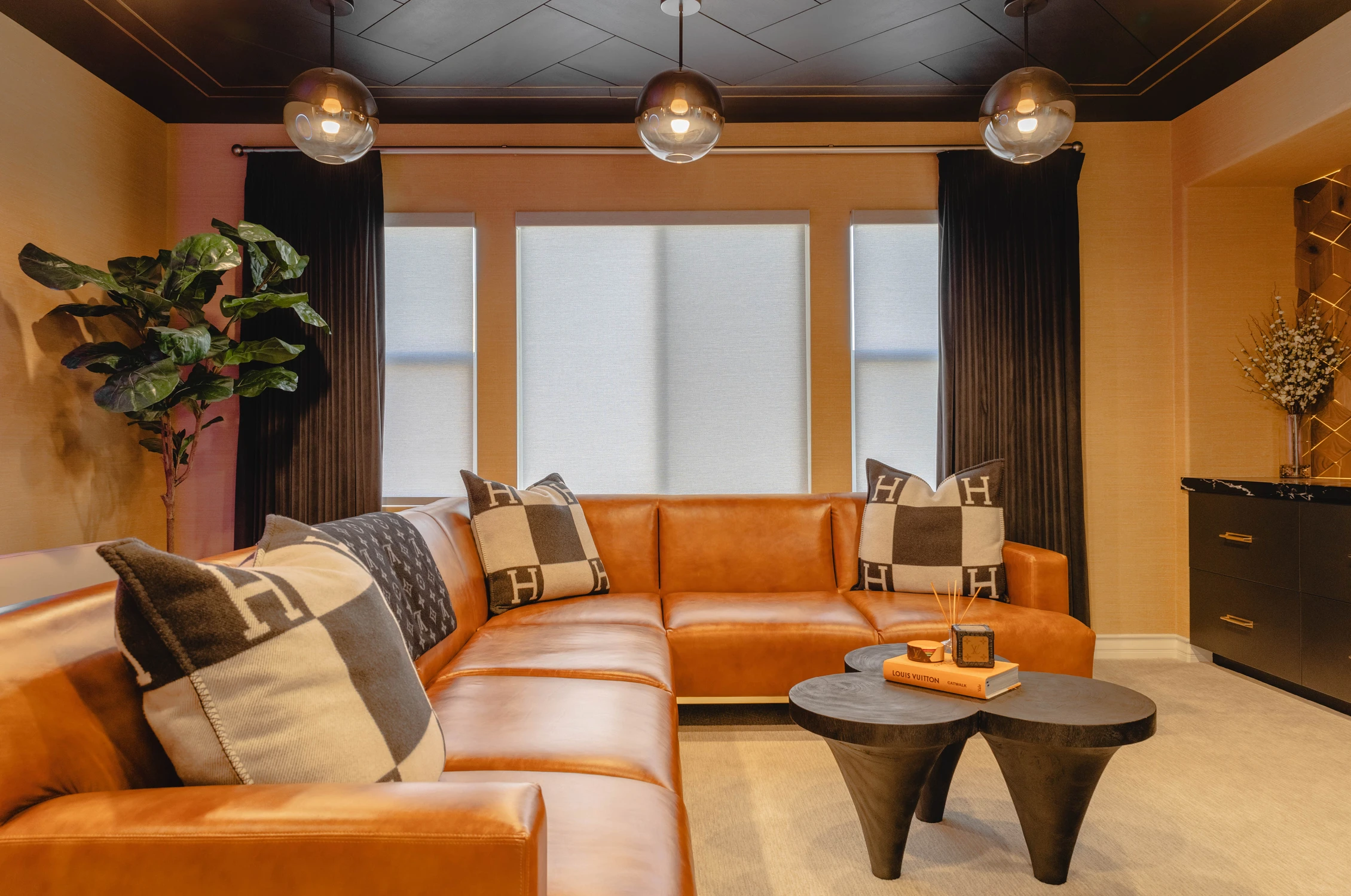 Orange leather sectional beneath smoked glass pendant lights