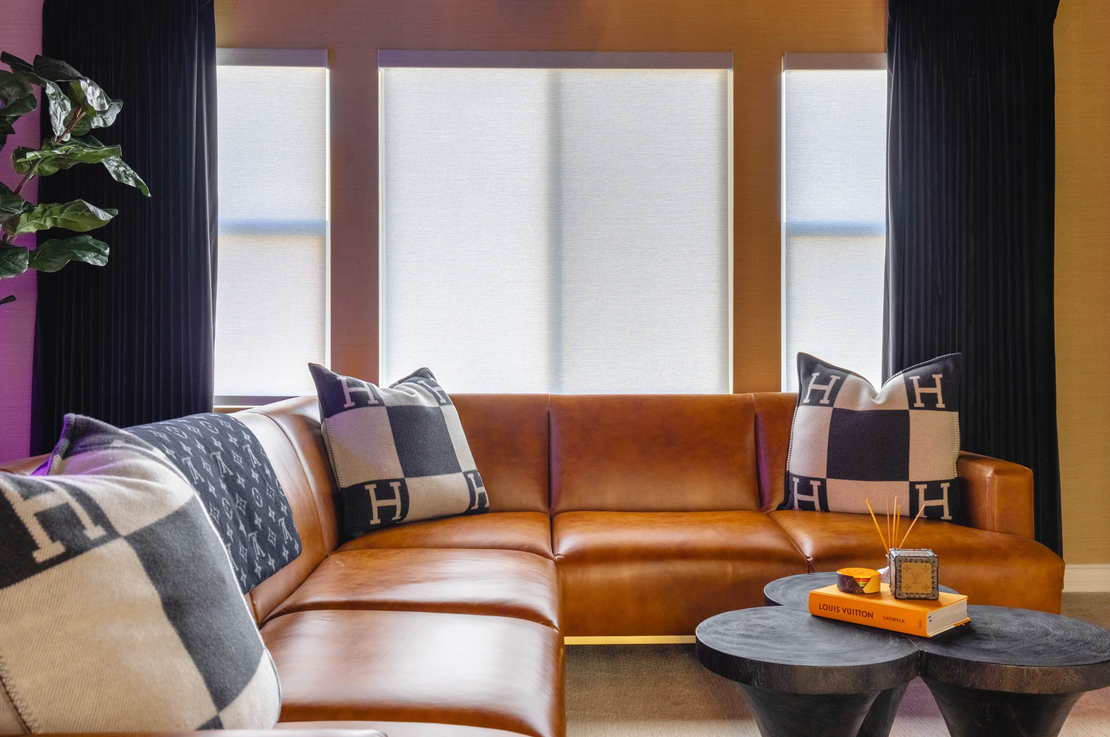 Orange leather sofa with dark drapery and layered pillows
