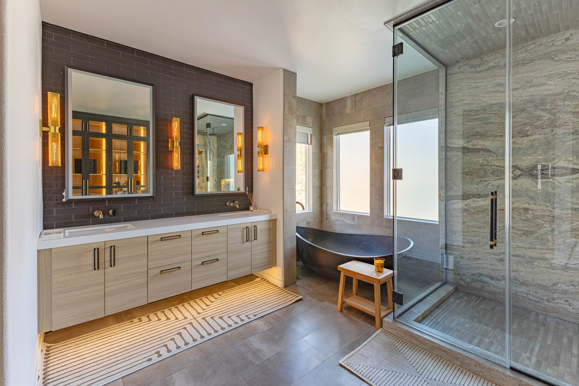 Primary bathroom with double vanity, black tub, and glass shower