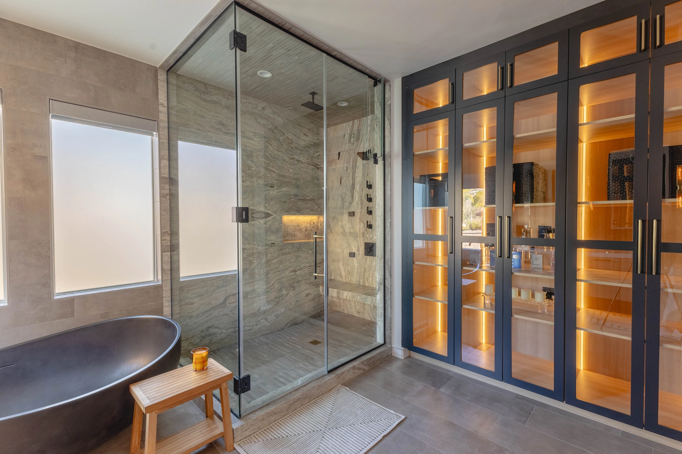 Primary bathroom with black tub, glass shower, and illuminated cabinet