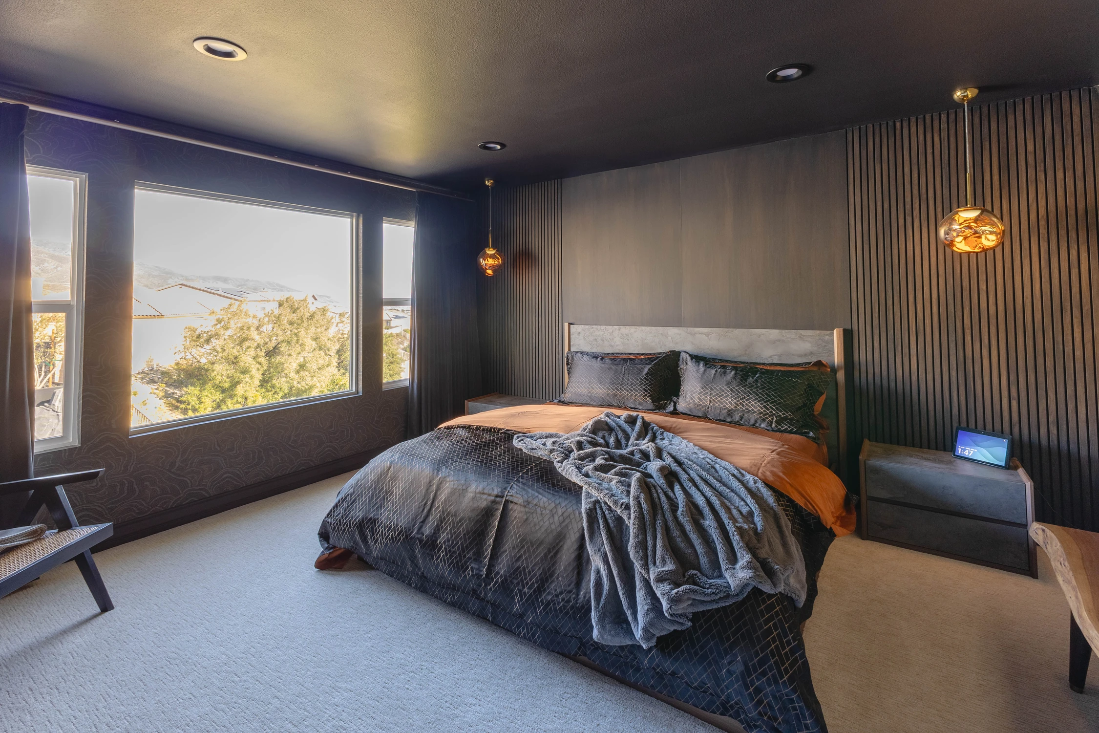 Dark bedroom with tall windows, paneled wall, and amber pendants